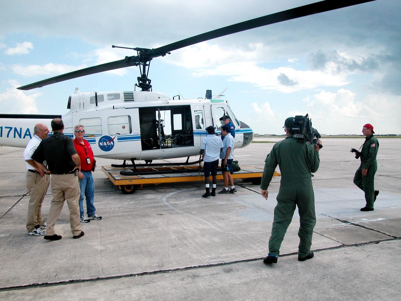 KENNEDY SPACE CENTER, FLA. - After Hurricane Jeanne, Center Director Jim Kennedy (in red shirt) is ready to board the nearby helicopter to observe storm damage around the Center. He will be accompanied by a KSC videographer and photographer to record the sites. A category 3 storm, Jeanne barreled through Central Florida Sept. 25-26, the fourth hurricane in 6 weeks to batter the state.