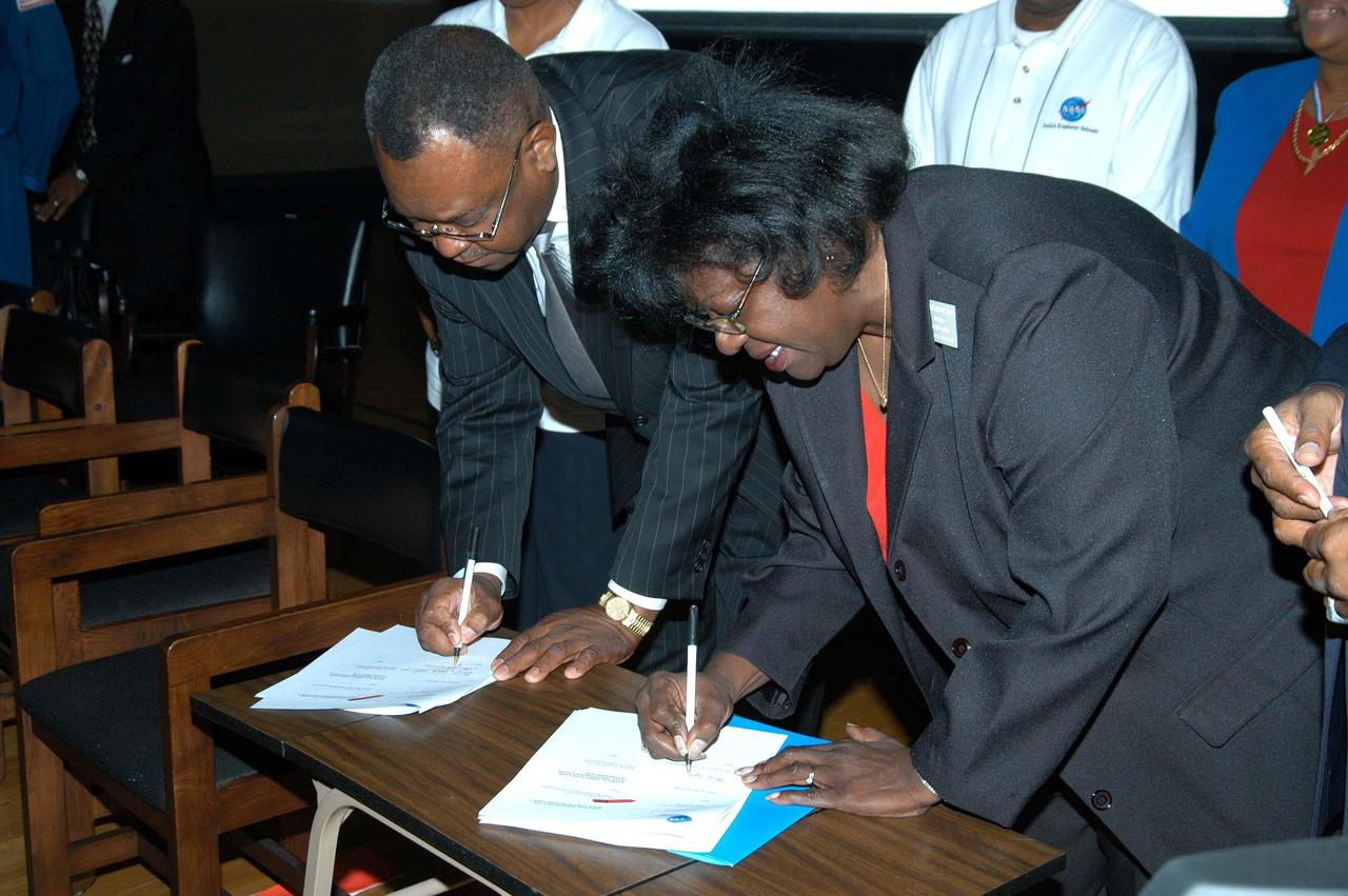 KENNEDY SPACE CENTER, FLA. -  Julian Earls (left), a school board member of Ronald E. McNair High School in Atlanta, and Sarah Copelin-Wood (far left), chair of the Board of Education, sign a Memorandum of Understanding after a presentation by KSC Deputy Director Dr. Woodrow Whitlow Jr., astronaut Leland Melvin and Dr. Julian Earls, director of NASA Glenn Research Center.  McNair is a NASA Explorer School (NES).  Whitlow visited the school to share the vision for space exploration with the next generation of explorers.  He talked with students about our destiny as explorers, NASA’s stepping stone approach to exploring Earth, the Moon, Mars and beyond, how space impacts our lives, and how people and machines rely on each other in space.  Dr. Earls discussed the future and the vision for space, plus the NASA careers needed to meet the vision.  Melvin talked about the importance of teamwork and what it takes for mission success.