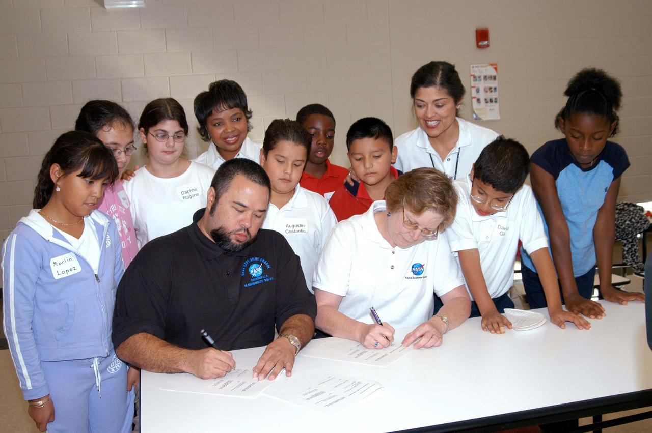KENNEDY SPACE CENTER, FLA. - Shawn McCollough, principal of Gainesville Elementary School, a NASA Explorer School (NES) in Gainesville, Ga., and a teacher sign a Memorandum of Understanding between KSC and the school for the NES program. Schools from across the country are eligible to apply online for an opportunity to partner with NASA in a program designed to bring engaging mathematics, science and technology learning to educators, students and families.