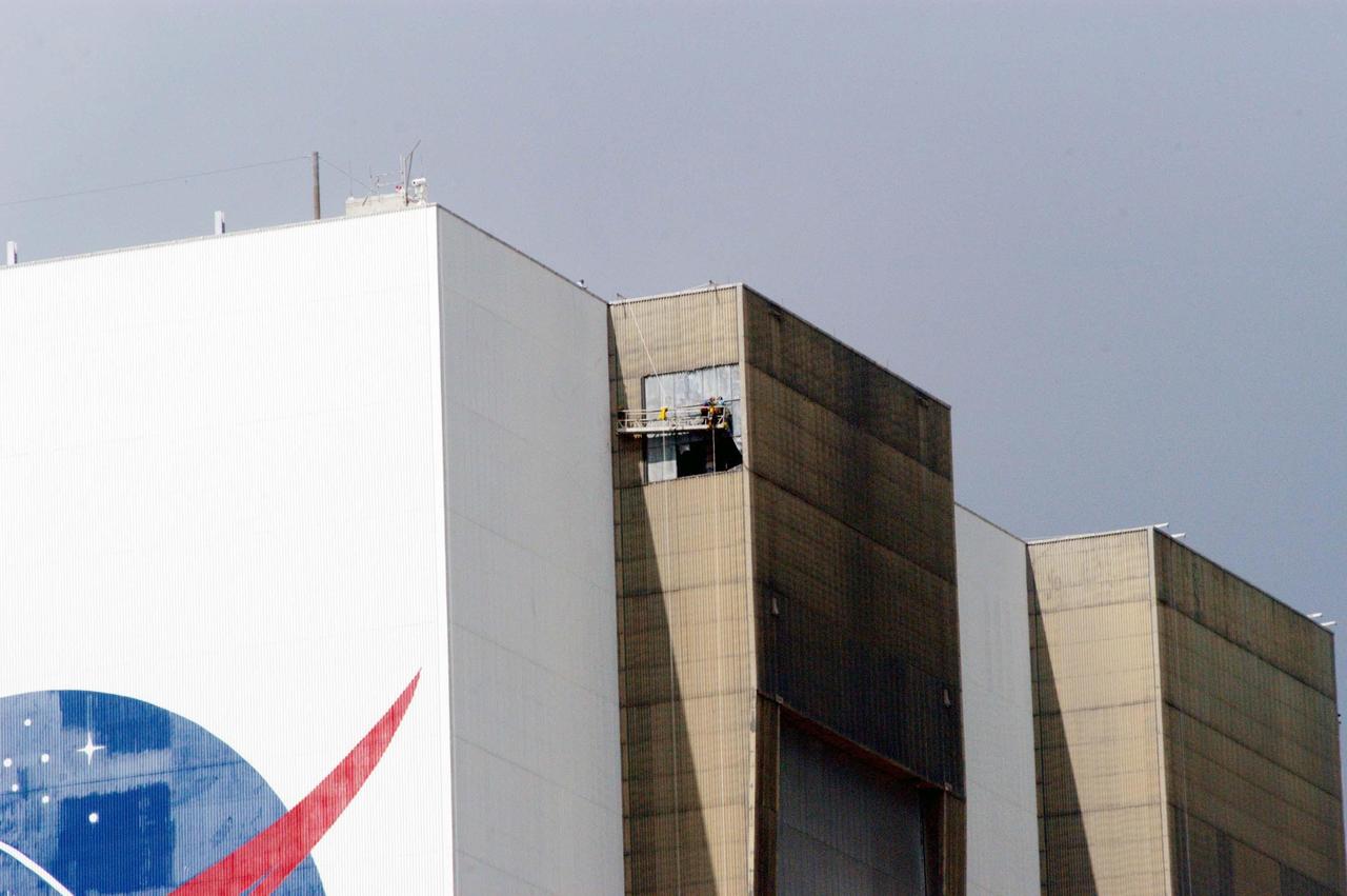 KENNEDY SPACE CENTER, FLA. - On a scaffold suspended near the top of the east side of the Vehicle Assembly Building, workers are covering the holes with corrugated steel so the facility can be returned to performing operational activities. The VAB lost 820 panels from the south wall during Hurricane Frances, and 25 additional panels during Hurricane Jeanne. The VAB stands 525 feet tall. Central Florida, including Kennedy Space Center, was battered by four hurricanes between Aug. 13 and Sept. 26.