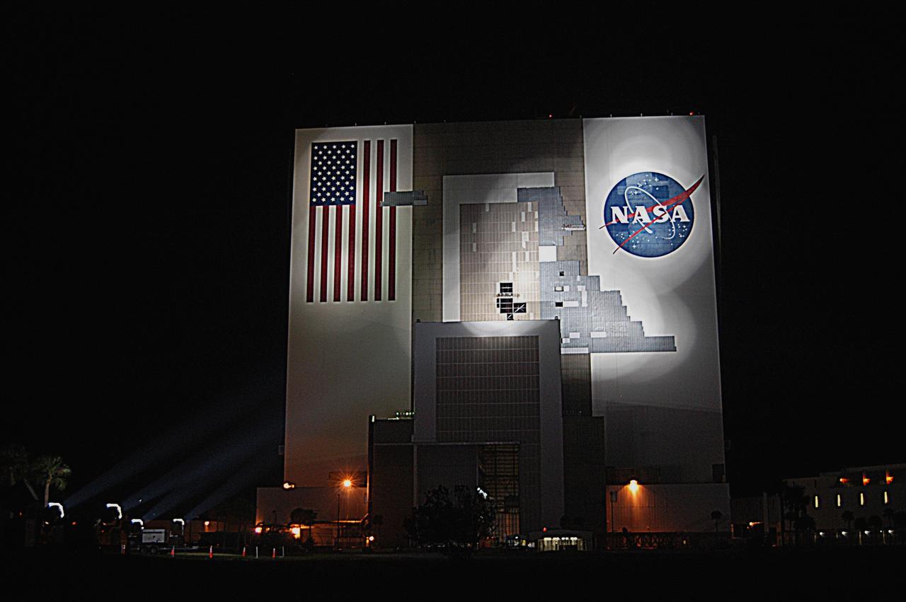 KENNEDY SPACE CENTER, FLA. - Xenon lights on the ground near the Vehicle Assembly Building bathe the south wall in light, allowing workers on scaffolds (center and upper right near the NASA logo) to cover the holes with corrugated steel so the facility can be returned to performing operational activities. The VAB lost 820 panels from the south wall during Frances, and 25 additional panels during Hurricane Jeanne. The VAB stands 525 feet tall. Central Florida, including Kennedy Space Center, was battered by four hurricanes between Aug. 13 and Sept. 26.