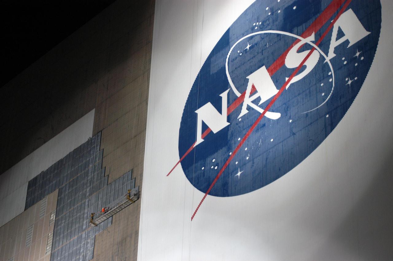 KENNEDY SPACE CENTER, FLA. - The south wall of the Vehicle Assembly Building is bathed in light at night to allow workers on a scaffold to cover the holes with corrugated steel so the facility can be returned to performing operational activities. Xenon lights on the ground provide the illumination. The VAB lost 820 panels from the south wall during Frances, and 25 additional panels during Hurricane Jeanne. The VAB stands 525 feet tall. Central Florida, including Kennedy Space Center, was battered by four hurricanes between Aug. 13 and Sept. 26.