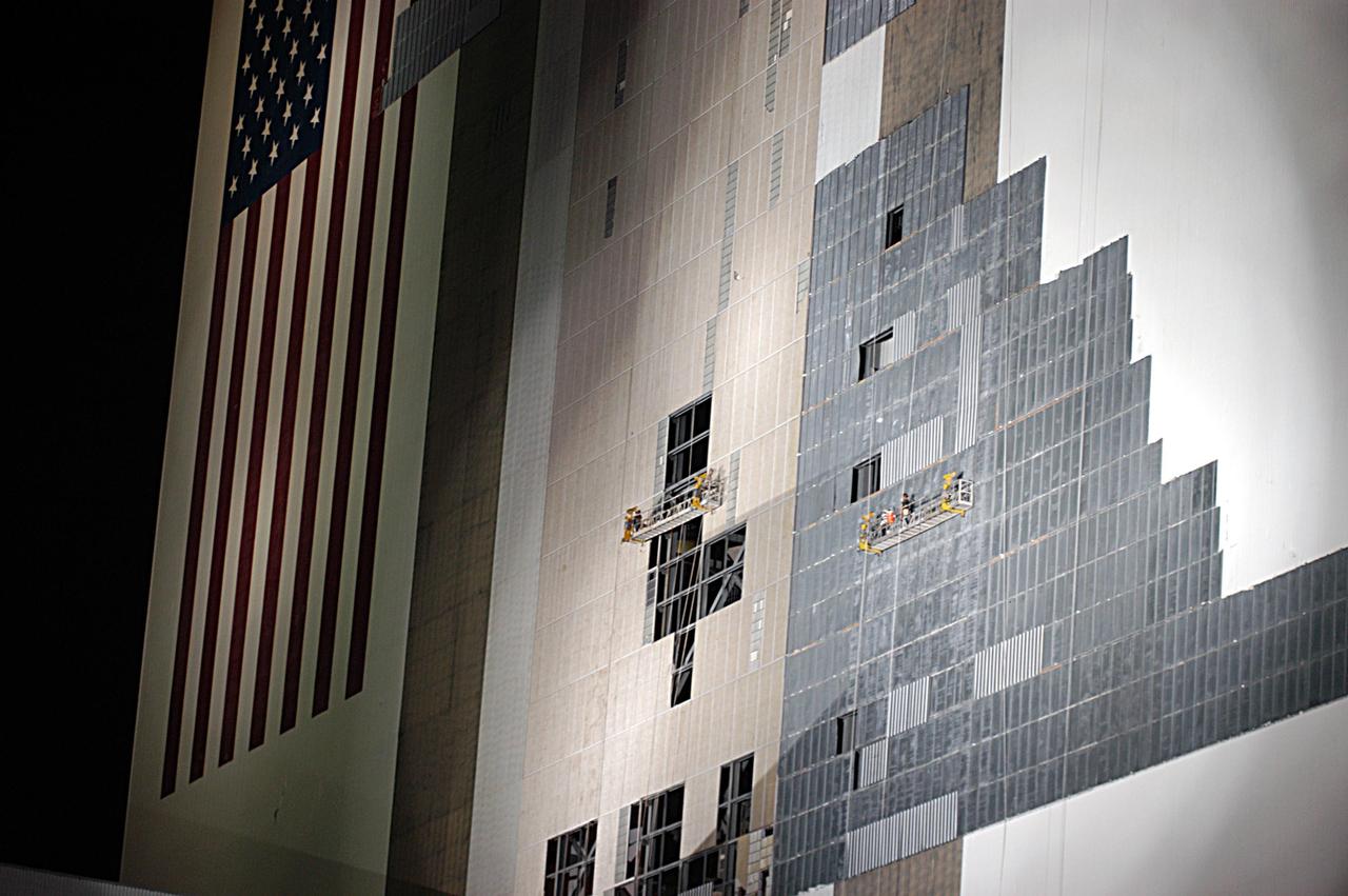 KENNEDY SPACE CENTER, FLA. - The south wall of the Vehicle Assembly Building is bathed in light at night to allow workers on two scaffolds to cover the holes with corrugated steel so the facility can be returned to performing operational activities. The VAB lost 820 panels from the south wall during Frances, and 25 additional panels during Hurricane Jeanne. The VAB stands 525 feet tall. Central Florida, including Kennedy Space Center, was battered by four hurricanes between Aug. 13 and Sept. 26.