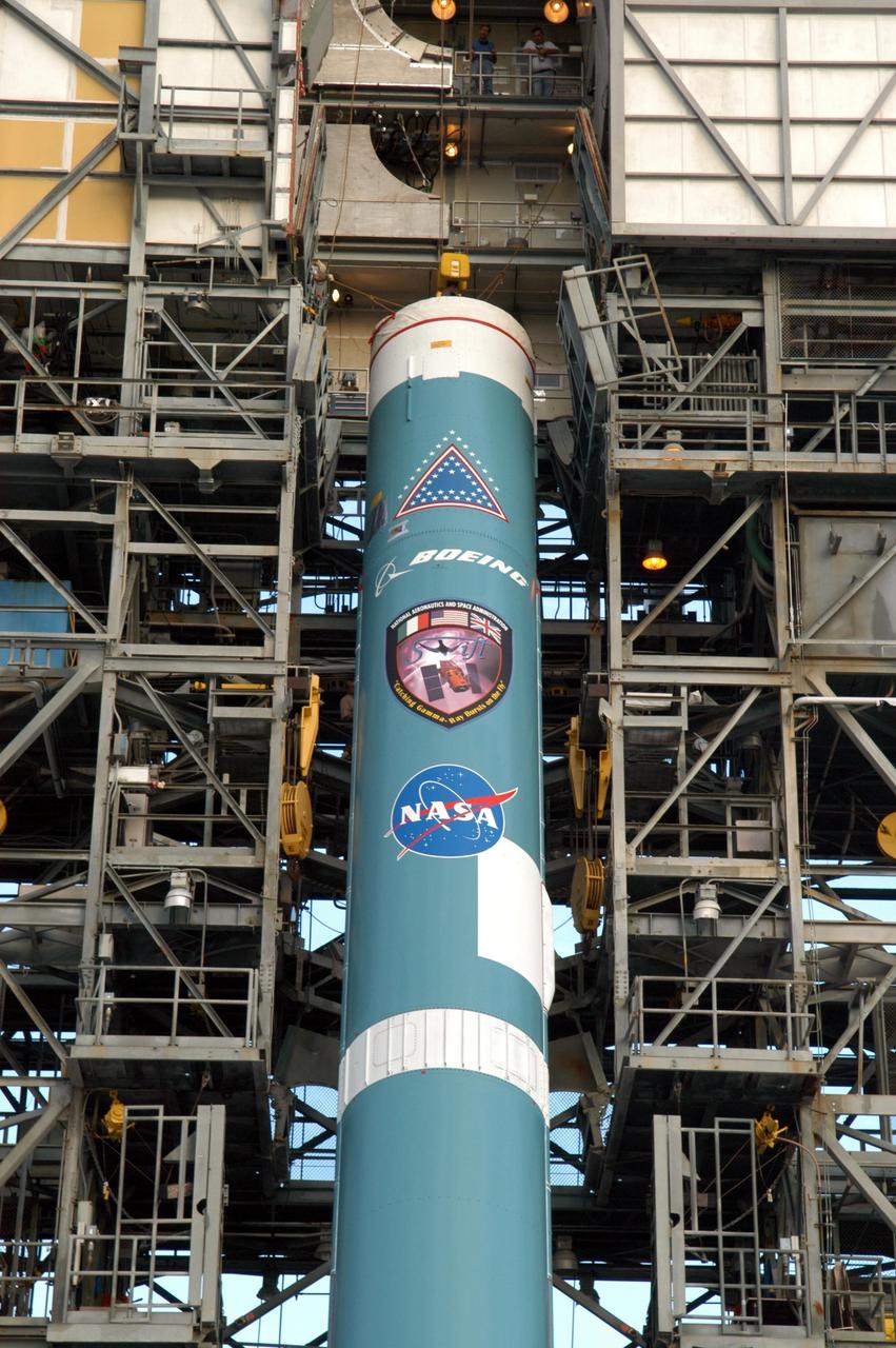 KENNEDY SPACE CENTER, FLA. -  On Launch Complex 17-A at Cape Canaveral Air Force Station, Fla., the first stage of a Boeing Delta II rocket is lifted toward the mobile service tower. To follow in the next week are attachment of the three strap-on solid rocket boosters, lifting of the payload fairing, and lifting of the second stage for mating with the first stage.   The rocket is the launch vehicle for the Swift spacecraft and its Gamma-Ray Burst Mission, now scheduled for liftoff no earlier than Nov. 2.  Swift is a medium-class Explorer mission managed by NASA’s Goddard Space Flight Center in Greenbelt, Md.  The observatory was built for NASA by Spectrum Astro, a division of General Dynamics.  KSC is responsible for Swift’s integration with the Boeing Delta II rocket and the countdown management on launch day.