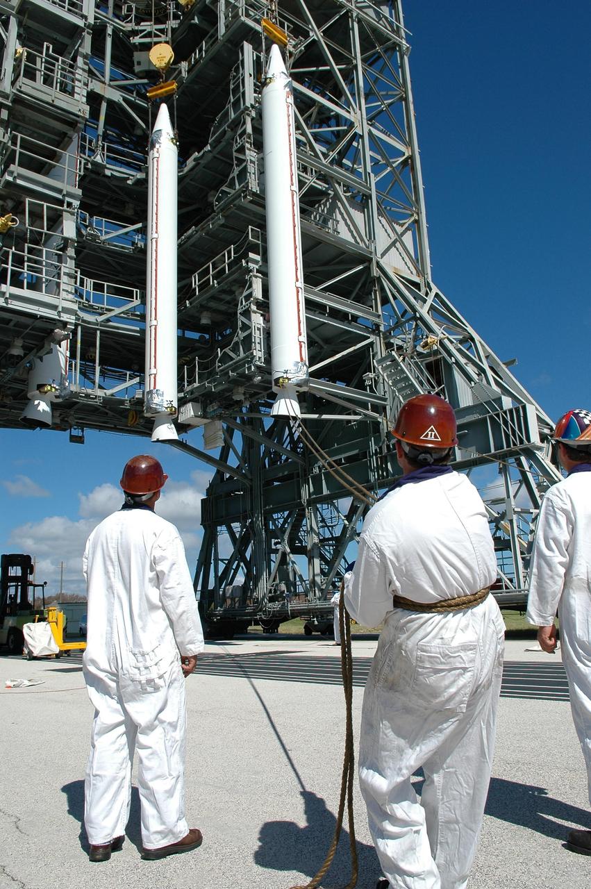 KENNEDY SPACE CENTER, FLA. - On Pad 17-A, Cape Canaveral Air Force Station, technicians on the ground hold guide ropes as a Solid Rocket Booster is lifted in to the mobile service tower. In all, three SRBs will be attached to the Boeing Delta launch vehicle for the Swift spacecraft and its Gamma-Ray Burst Mission. Swift is a medium-class Explorer mission managed by NASA’s Goddard Space Flight Center in Greenbelt, Md.