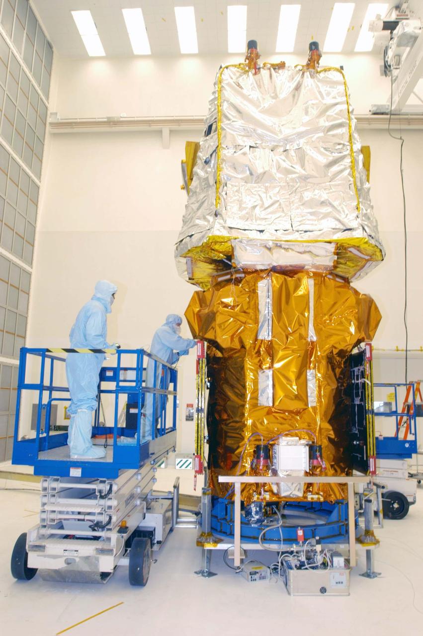 KENNEDY SPACE CENTER, FLA. - Quality Assurance Services technicians Willy Jones and Brian Kittle do some touch-up work on the Swift spacecraft in Hangar AE at Cape Canaveral Air Force Station. Swift has been wrapped with blankets to provide thermal stability during the mission.  Swift is a first-of-its-kind multi-wavelength observatory dedicated to the study of gamma-ray burst (GRB) science. Its three instruments will work together to observe GRBs and afterglows in the gamma-ray, X-ray, ultraviolet and optical wavebands. The most comprehensive study of GRB afterglows to date, Swift is expected to observe more than 200 gamma-ray bursts during its 2-year mission.