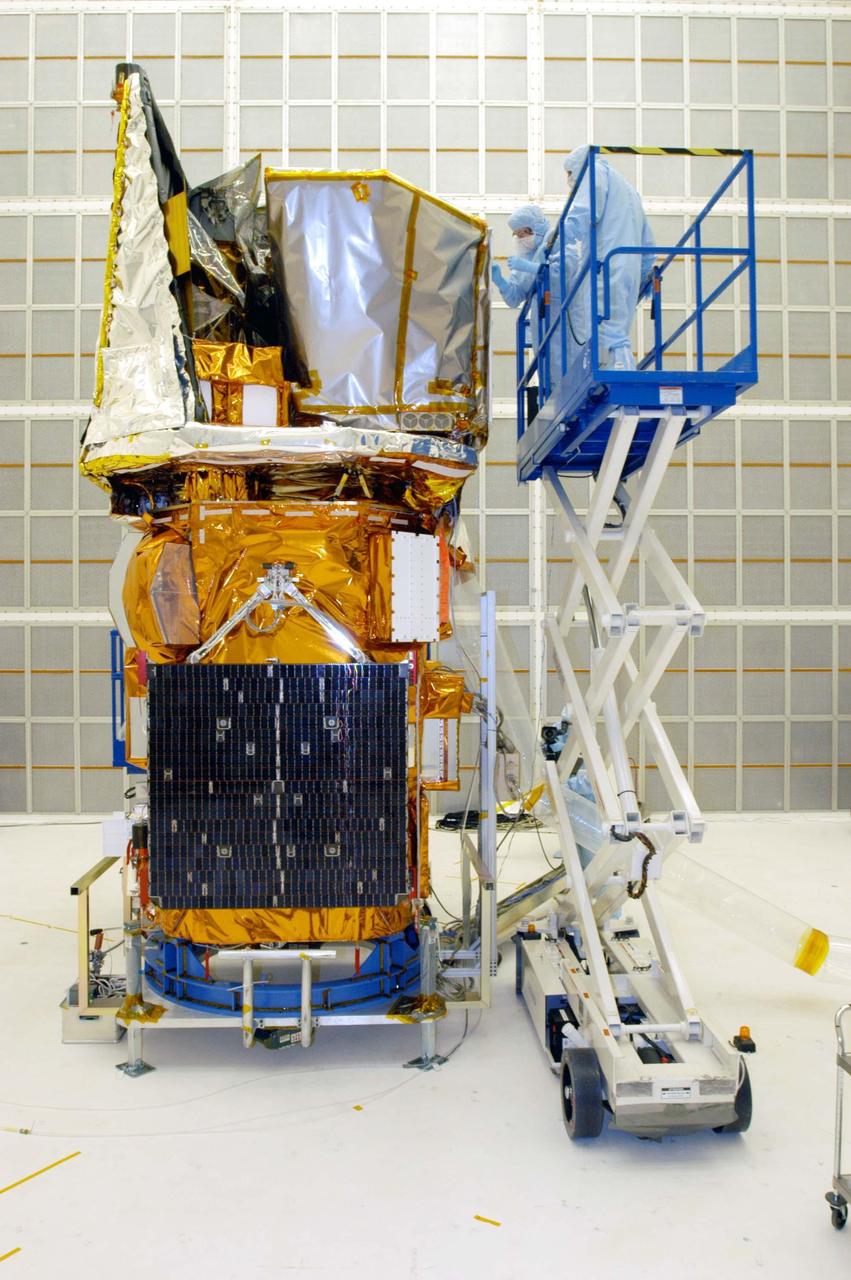 KENNEDY SPACE CENTER, FLA. - Technician Grace Miller-Swales (left) does touch-up work on the Swift spacecraft in Hangar AE at Cape Canaveral Air Force Station. John DiBatilito, with Quality Assurance Services, is at right.  Swift is wrapped with blankets to provide thermal stability during the mission.  Swift is a first-of-its-kind multi-wavelength observatory dedicated to the study of gamma-ray burst (GRB) science. Its three instruments will work together to observe GRBs and afterglows in the gamma-ray, X-ray, ultraviolet and optical wavebands. The most comprehensive study of GRB afterglows to date, Swift is expected to observe more than 200 gamma-ray bursts during its 2-year mission.