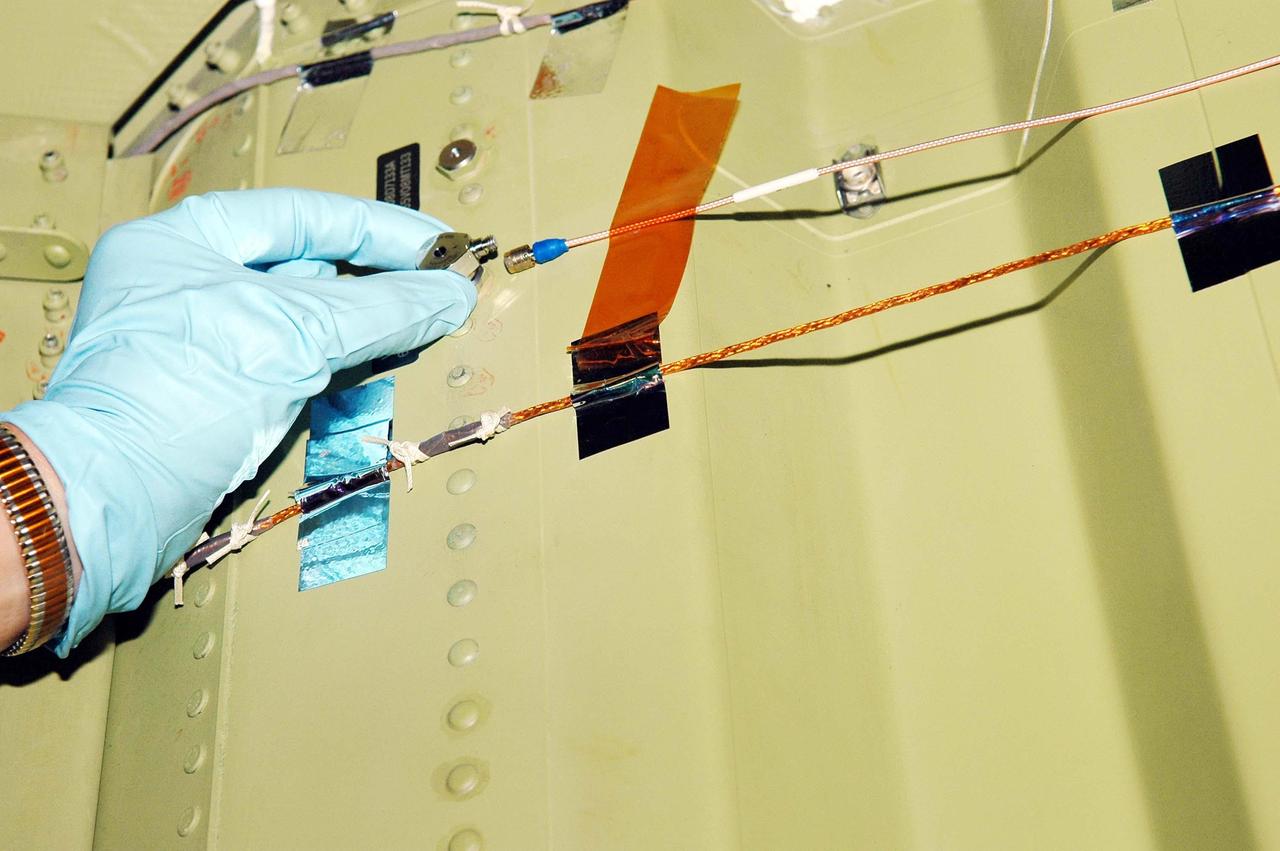 KENNEDY SPACE CENTER, FLA.  - In an installation demonstration in the Orbiter Processing Facility, a sensor is placed on the wing leading edge of orbiter Discovery.  The sensors are part of the Wing Leading Edge Impact Detection System, a new safety measure added for all future Space Shuttle missions. The system also includes accelerometers that monitor the orbiter's wings for debris impacts during launch and while in orbit. There are 22 temperature sensors and 66 accelerometers on each wing. Sensor data will flow from the wing to the crew compartment, where it will be transmitted to Earth.