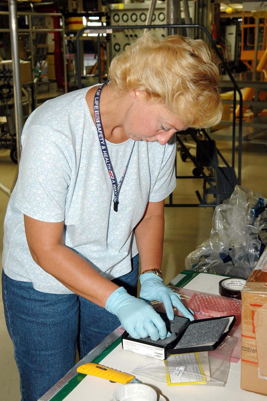 KENNEDY SPACE CENTER, FLA. - During an installation demonstration the Orbiter Processing Facility, United Space Alliance technician Lisa Campbell handles components of the sensor system being placed on the wing leading edge of orbiter Discovery. The sensors are part of the Wing Leading Edge Impact Detection System, a new safety measure added for all future Space Shuttle missions. The system also includes accelerometers that monitor the orbiter's wings for debris impacts during launch and while in orbit. There are 22 temperature sensors and 66 accelerometers on each wing. Sensor data will flow from the wing to the crew compartment, where it will be transmitted to Earth.