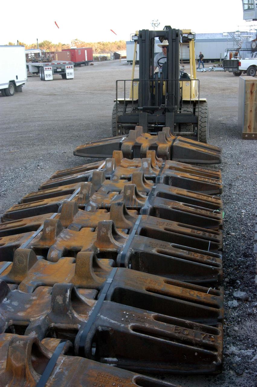 KENNEDY SPACE CENTER, FLA. - In the Crawler Transporter (CT) area, a worker places another load of new crawler shoes on the ground. The new shoes were manufactured by ME Global in Duluth, Minn. The CT transports the Mobile Launcher Platform, with the assembled Space Shuttle aboard, between the refurbishment area, the VAB and Launch Complex Pads 39A and 39B. The crawlers have 456 shoes, 57 per belt (8 belts in all). Each shoe weighs 2,200 pounds. The original shoes were manufactured for the Apollo Program. Cracks appeared in the shoes in recent years spurring a need for replacement. The new manufacturer, in Duluth, Minn., has improved the design for Return to Flight and use through the balance of the Space Shuttle Program.