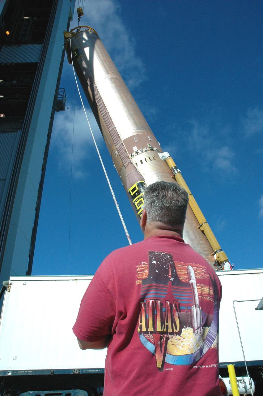 KENNEDY SPACE CENTER, FLA. - On Launch Complex 41 at Cape Canaveral Air Force Station, a worker stands by as the first stage of an Atlas V rocket is raised to vertical. The rocket will then be moved into the Vertical Integration Facility to begin preparations for launch. The Lockheed Martin Atlas V is the launch vehicle for the New Horizons spacecraft, which is designed to make the first reconnaissance of Pluto and Charon - a "double planet" and the last planet in our solar system to be visited by spacecraft. The mission will then visit one or more objects in the Kuiper Belt region beyond Neptune. New Horizons is scheduled to launch in January 2006, swing past Jupiter for a gravity boost and scientific studies in February or March 2007, and reach Pluto and its moon, Charon, in July 2015.