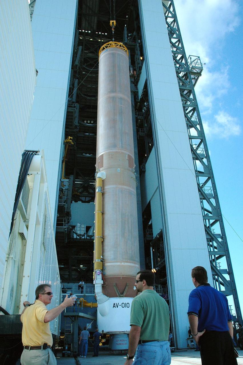 KENNEDY SPACE CENTER, FLA. -  After being raised to a vertical position, the first stage of an Atlas V rocket is being moved into the Vertical Integration Facility to begin preparations for launch on Launch Complex 41 at Cape Canaveral Air Force Station.  The Lockheed Martin Atlas V is the launch vehicle for the New Horizons spacecraft, which is designed to make the first reconnaissance of Pluto and Charon - a "double planet" and the last planet in our solar system to be visited by spacecraft. The mission will then visit one or more objects in the Kuiper Belt region beyond Neptune. New Horizons is scheduled to launch in January 2006, swing past Jupiter for a gravity boost and scientific studies in February or March 2007, and reach Pluto and its moon, Charon, in July 2015.