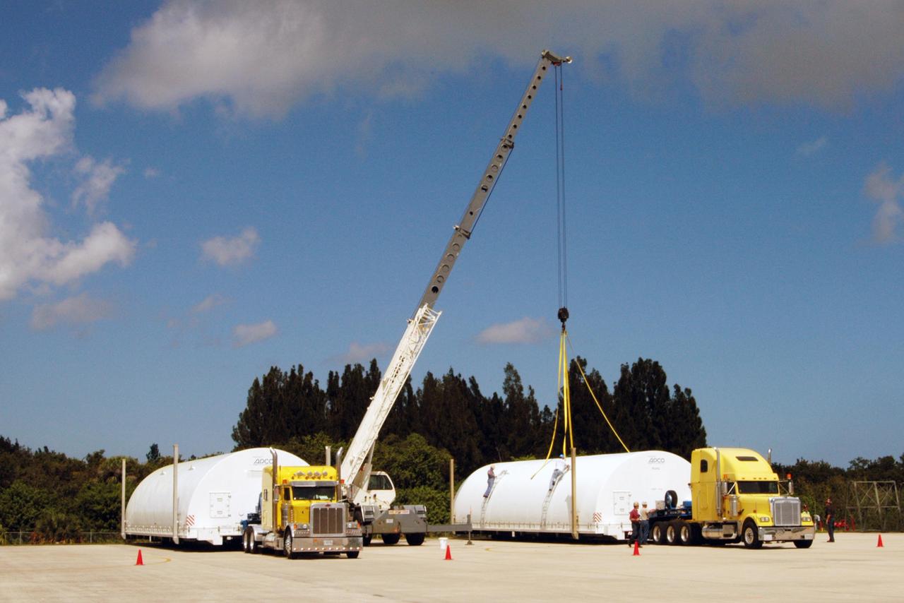 KENNEDY SPACE CENTER, FLA. - On the Shuttle Landing Facility at NASA Kennedy Space Center, the Atlas V fairing halves for the New Horizons spacecraft are being covered by a protective container before their transport to Astrotech Space Operations in Titusville. The fairing later will be placed around the New Horizons spacecraft in the Payload Hazardous Service Facility. The fairing later will be placed around the New Horizons spacecraft in the Payload Hazardous Service Facility. A fairing protects a spacecraft during launch and flight through the atmosphere. Once in space, it is jettisoned. The Lockheed Martin Atlas V is the launch vehicle for the New Horizons spacecraft, which is designed to make the first reconnaissance of Pluto and Charon - a "double planet" and the last planet in our solar system to be visited by spacecraft. The mission will then visit one or more objects in the Kuiper Belt region beyond Neptune. New Horizons is scheduled to launch in January 2006, swing past Jupiter for a gravity boost and scientific studies in February or March 2007, and reach Pluto and its moon, Charon, in July 2015.