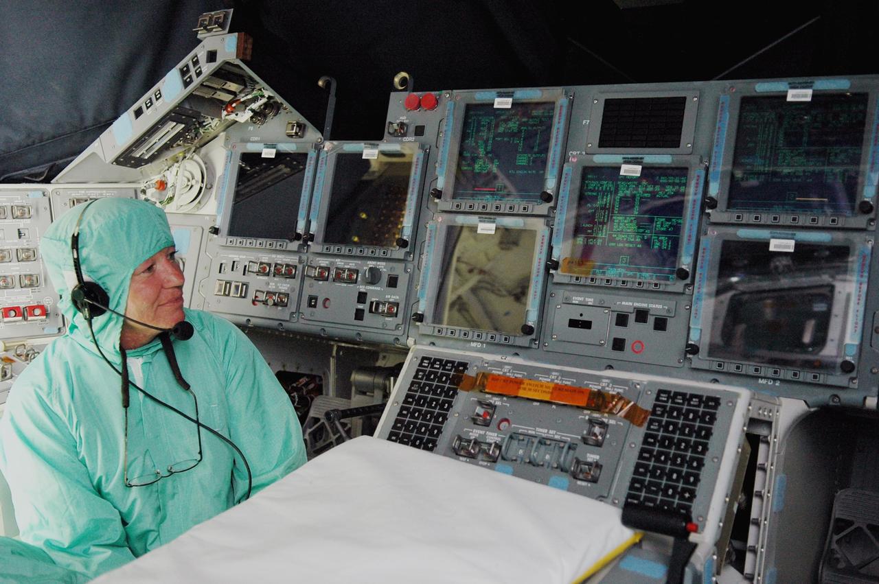 KENNEDY SPACE CENTER, FLA. -   In Orbiter Processing Facility bay 2, United Space Alliance technician Loralee Woodbury monitors the lighted display in Space Shuttle Endeavour's cockpit after full powerup, the first time the orbiter has been powered up after nearly two years. Endeavour has been in its Orbiter Major Modification (OMM) period since December 2003. Engineers and technicians spent 900,000 hours performing 124 modifications to the vehicle. These included all recommended return to flight safety modifications, bonding more than 1,000 thermal protection system tiles and inspecting more than 150 miles of wiring throughout Endeavour. Eighty five of the modifications are completed, with work on the additional 39 modifications continuing throughout the next few months. Shuttle major modification periods are scheduled at regular intervals to enhance safety and performance, infuse new technology and allow for thorough inspections of the airframe and wiring of the vehicles. This was the second of these modification periods performed entirely at Kennedy Space Center. Endeavour's previous modification was completed in March 1997.