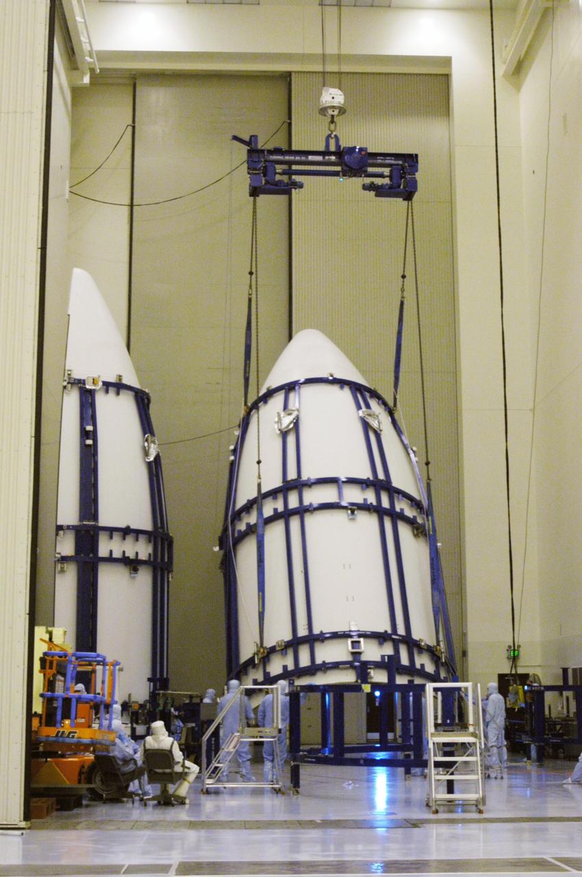 KENNEDY SPACE CENTER, FLA. - In the NASA Kennedy Space Center’s Payload Hazardous Servicing Facility, one part of the fairing to be placed around the New Horizons spacecraft is lifted from a stand. The fairing encapsulates the spacecraft to protect it during launch and flight through the atmosphere. Once out of the atmosphere, the fairing is jettisoned. New Horizons will make the first reconnaissance of Pluto and Charon - a "double planet" and the last planet in our solar system to be visited by spacecraft. The mission will then visit one or more objects in the Kuiper Belt region beyond Neptune. SWAP is a solar wind and plasma spectrometer that measures atmospheric “escape rate” and will observe Pluto’s interaction with the solar wind. New Horizons is scheduled to launch in January 2006, swing past Jupiter for a gravity boost and scientific studies in February or March 2007, and reach Pluto and its moon, Charon, in July 2015.