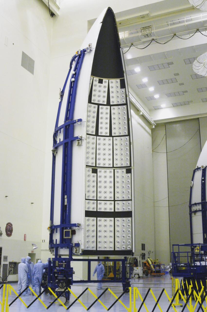 KENNEDY SPACE CENTER, FLA. - In the NASA Kennedy Space Center’s Payload Hazardous Servicing Facility, one part of the Lockheed Martin Atlas V rocket fairing to be placed around the New Horizons spacecraft is moved into place for encapsulation. The fairing encloses the spacecraft to protect it during launch and flight through the atmosphere. Once out of the atmosphere, the fairing is jettisoned. New Horizons will make the first reconnaissance of Pluto and Charon - a "double planet" and the last planet in our solar system to be visited by spacecraft. The mission will then visit one or more objects in the Kuiper Belt region beyond Neptune. SWAP is a solar wind and plasma spectrometer that measures atmospheric “escape rate” and will observe Pluto’s interaction with the solar wind. New Horizons is scheduled to launch in January 2006, swing past Jupiter for a gravity boost and scientific studies in February or March 2007, and reach Pluto and its moon, Charon, in July 2015.