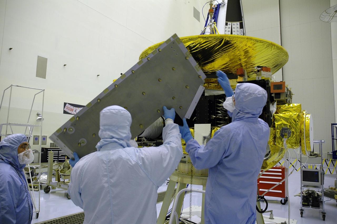 KENNEDY SPACE CENTER, FLA. - At NASA Kennedy Space Center’s Payload Hazardous Servicing Facility, a technician from the Applied Physics Laboratory works on the New Horizons spacecraft before installing one of the panels. A series of interconnecting panels will enclose the spacecraft beneath the antenna to maintain safe operating temperatures in space. New Horizons will make the first reconnaissance of Pluto and its moon, Charon - a "double planet" and the last planet in our solar system to be visited by spacecraft. As it approaches Pluto, the spacecraft will look for ultraviolet emission from Pluto's atmosphere and make the best global maps of Pluto and Charon in green, blue, red and a special wavelength that is sensitive to methane frost on the surface. It will also take spectral maps in the near infrared, telling the science team about Pluto's and Charon's surface compositions and locations and temperatures of these materials. When the spacecraft is closest to Pluto or its moon, it will take close-up pictures in both visible and near-infrared wavelengths. The mission will then visit one or more objects in the Kuiper Belt region beyond Neptune. New Horizons is scheduled to launch in January 2006, swing past Jupiter for a gravity boost and scientific studies in February or March 2007, and reach Pluto and Charon in July 2015.