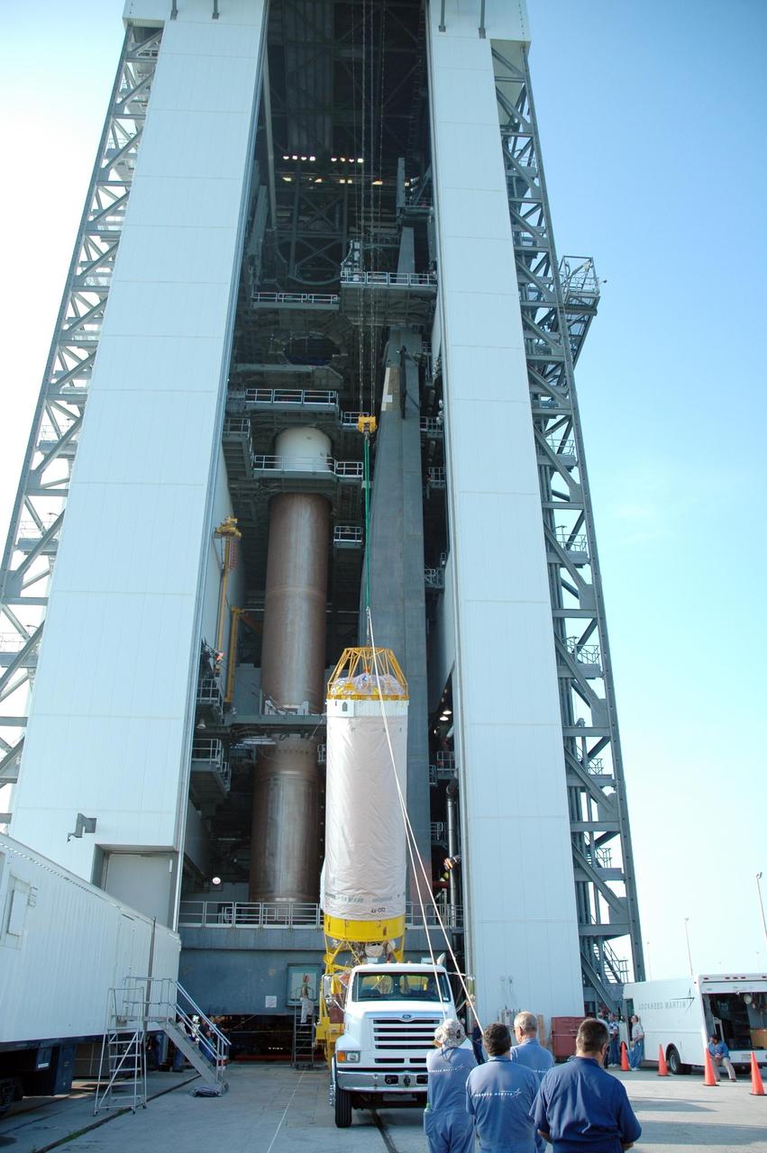 KENNEDY SPACE CENTER, FLA. -  In front of the mobile service tower on Launch Complex 41 at Cape Canaveral Air Force Station in Florida, workers complete the raising of the Lockheed Martin Atlas V Centaur stage to a vertical position.  The second stage of the launch vehicle for the New Horizons spacecraft, the Centaur will be mated with the waiting first stage, seen behind it at left.   New Horizons will make the first reconnaissance of Pluto and its moon, Charon - a "double planet" and the last planet in our solar system to be visited by spacecraft. As it approaches Pluto, the spacecraft will look for ultraviolet emission from Pluto's atmosphere and make the best global maps of Pluto and Charon in green, blue, red and a special wavelength that is sensitive to methane frost on the surface. It will also take spectral maps in the near infrared, telling the science team about Pluto's and Charon's surface compositions and locations and temperatures of these materials. When the spacecraft is closest to Pluto or its moon, it will take close-up pictures in both visible and near-infrared wavelengths. The mission will then visit one or more objects in the Kuiper Belt region beyond Neptune. New Horizons is scheduled to launch in January 2006, swing past Jupiter for a gravity boost and scientific studies in February or March 2007, and reach Pluto and Charon in July 2015.
