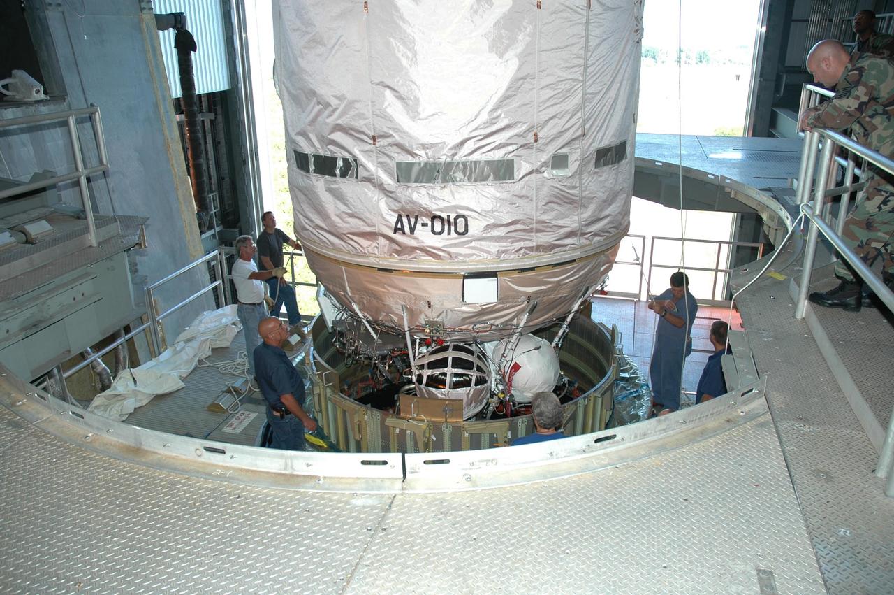 KENNEDY SPACE CENTER, FLA. - Inside the mobile service tower on Launch Complex 41 at Cape Canaveral Air Force Station in Florida, workers oversee the lowering of the Lockheed Martin Atlas V Centaur stage (above) toward the first stage. The two stages will be mated. The Atlas V is the launch vehicle for the New Horizons spacecraft. New Horizons will make the first reconnaissance of Pluto and its moon, Charon - a "double planet" and the last planet in our solar system to be visited by spacecraft. As it approaches Pluto, the spacecraft will look for ultraviolet emission from Pluto's atmosphere and make the best global maps of Pluto and Charon in green, blue, red and a special wavelength that is sensitive to methane frost on the surface. It will also take spectral maps in the near infrared, telling the science team about Pluto's and Charon's surface compositions and locations and temperatures of these materials. When the spacecraft is closest to Pluto or its moon, it will take close-up pictures in both visible and near-infrared wavelengths. The mission will then visit one or more objects in the Kuiper Belt region beyond Neptune. New Horizons is scheduled to launch in January 2006, swing past Jupiter for a gravity boost and scientific studies in February or March 2007, and reach Pluto and Charon in July 2015.