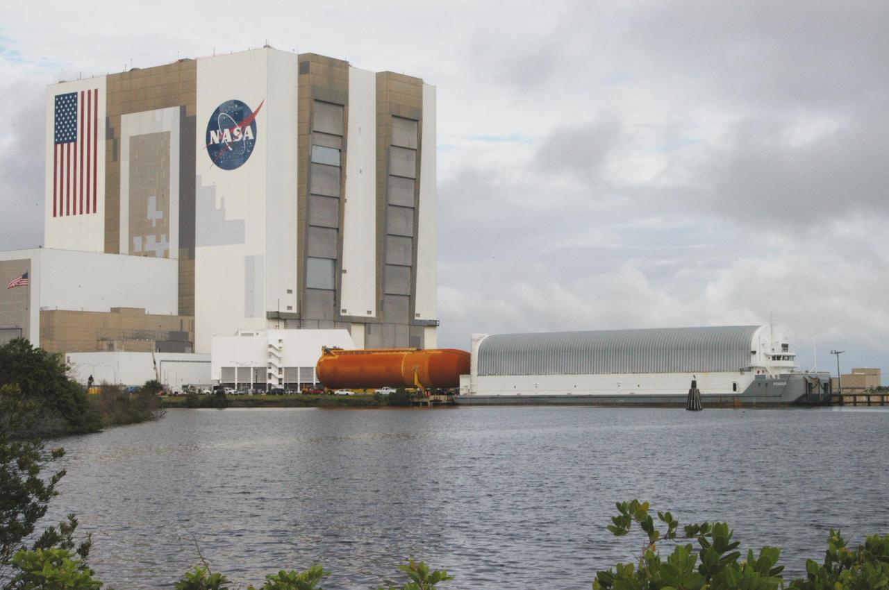 KENNEDY SPACE CENTER, FLA. -  After leaving NASA Kennedy Space Center’s Vehicle Assembly Building (in the background), external tank 120 approaches the Turn Basin and the waiting barge Pegasus (at right).  The tank will be loaded onto the barge for transport to NASA’s Michoud Assembly Facility in Louisiana for additional modifications.  This tank is the first of the newly designed tanks that were delivered to Kennedy.  Previously, the tank was stacked with Discovery and, more recently, Atlantis.  The tank has already gone through two tanking cycles during tanking tests but was replaced with tank #121 for Discovery’s return to flight mission STS-114.