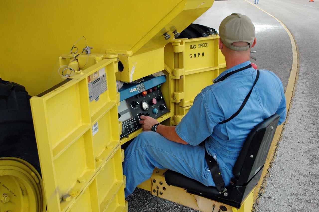 KENNEDY SPACE CENTER, FLA. -  One of the operators of the external tank transporter sits on the side of the vehicle.  Carrying external tank #120, the transporter is making the turn toward the nearby Turn Basin.  The tank will be loaded onto the barge Pegasus for towing to NASA’s Michoud Assembly Facility in Louisiana for additional modifications.  This tank is the first of the newly designed tanks that were delivered to Kennedy.  Previously, the tank was stacked with Discovery and, more recently, Atlantis.  The tank has already gone through two tanking cycles during tanking tests but was replaced with tank #121 for Discovery’s return to flight mission STS-114.