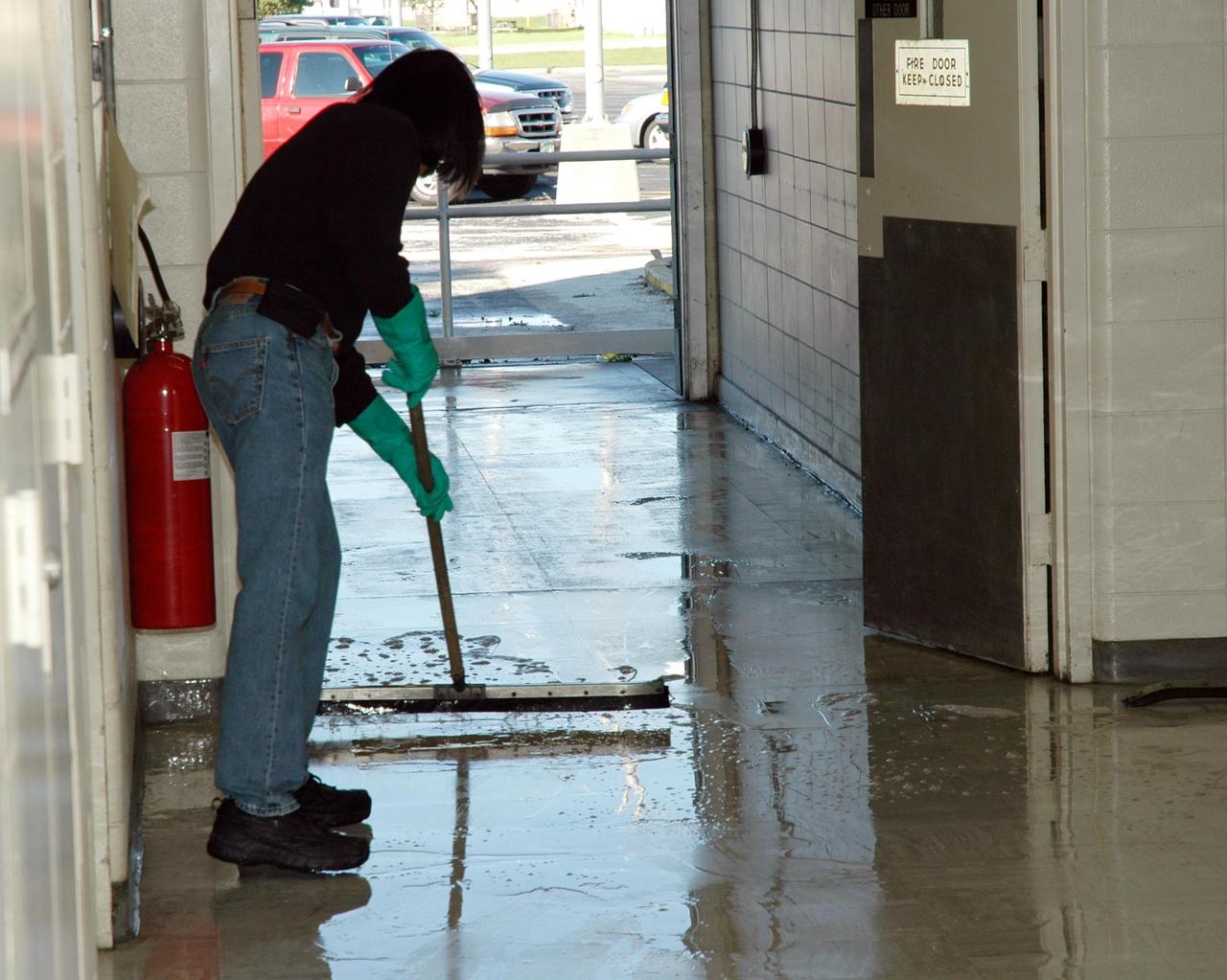 KENNEDY SPACE CENTER, FLA. -   A worker at the NASA Kennedy Space Center sweeps water out the door of a building following the wrath of hurricane Wilma as it crossed the state Oct. 24.  Kennedy’s facilities sustained minor structural damage,  primarily to roofs or from water intrusion. The Vehicle Assembly Building lost some panels on the east and west sides. Some facilities lost power. A total of 13.6 inches of rain was recorded at the Shuttle Landing Facility. The highest wind gust recorded was 94 mph from the north-northwest at Launch Pad 39B, while the maximum sustained wind was 76 mph from the north-northwest at the top of the 492-foot weather tower located north of the Vehicle Assembly Building.