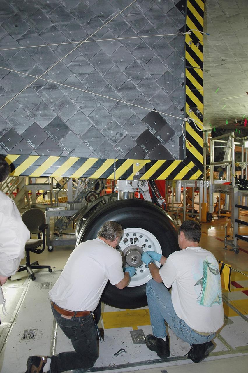 KENNEDY SPACE CENTER, FLA. - In NASA’s Orbiter Processing Facility Bay 3, United Space Alliance senior shuttle machinist Jake Jackson (left) installs and torques flight tires on Discovery. Discovery processing is under way for the second return to flight test mission, STS-121.