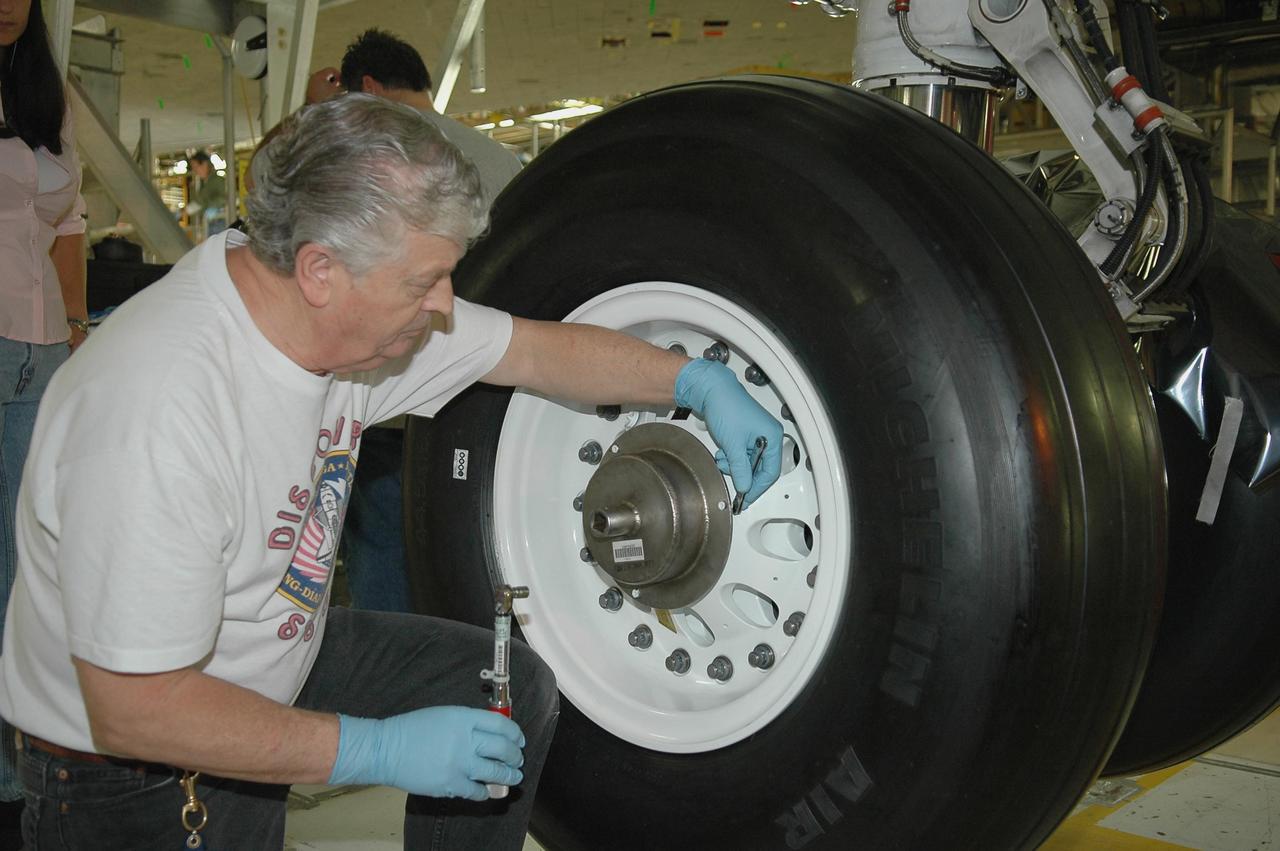KENNEDY SPACE CENTER, FLA. - In NASA’s Orbiter Processing Facility Bay 3, United Space Alliance senior shuttle machinist Jake Jackson checks the torque on a newly installed flight tire on Discovery. Discovery processing is under way for the second return to flight test mission, STS-121.
