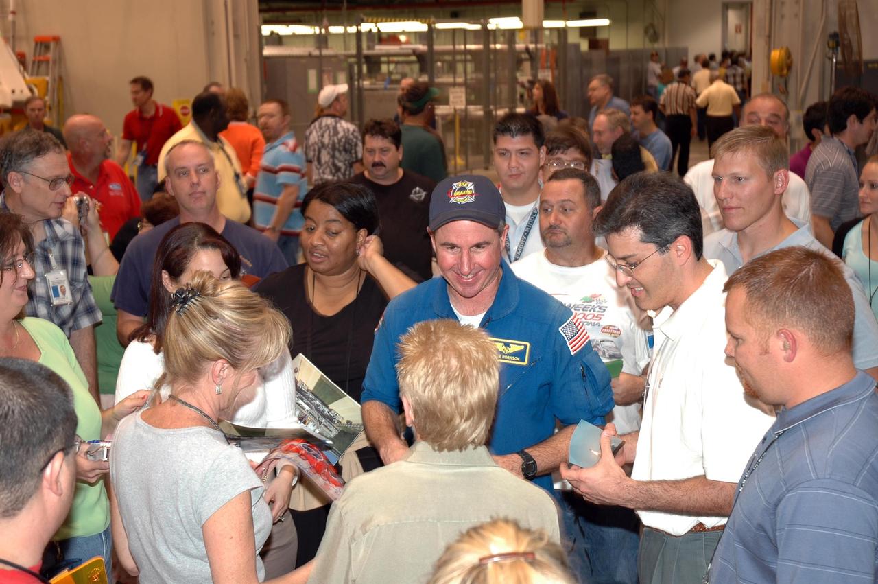KENNEDY SPACE CENTER, FLA. -  In NASA Kennedy Space Center’s Assembly and  Refurbishment Facility, employees crowd around STS-114 Mission Specialist Stephen Robinson as he signs mementos for them.  Robinson joined Mission Specialist Soichi Noguchi to talk to the employees about their successful mission.  They and other crew members are visiting several sites during their return to Kennedy Space Center. They have returned to Florida especially for a celebration in the KSC Visitor Complex of the successful return to flight mission that launched July 26 of this year.