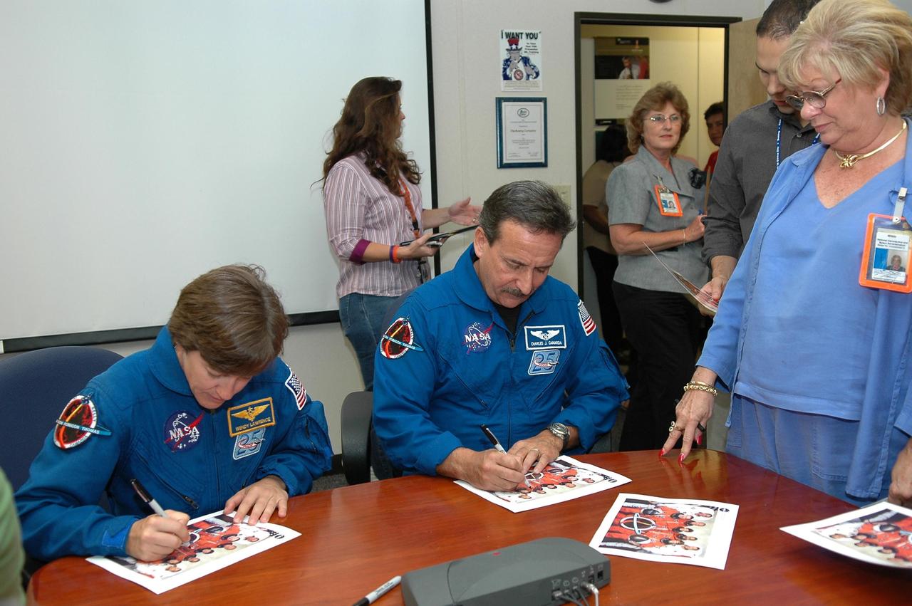 KENNEDY SPACE CENTER, FLA. - After speaking to the employees in the Space Station Processing Facility, STS-114 Mission Specialists Wendy Lawrence and Charles Camarda autograph crew photos. They and the other crew members visited several sites during their return to the Center. Their return is being celebrated at a gathering at the KSC Visitor Complex later this evening.