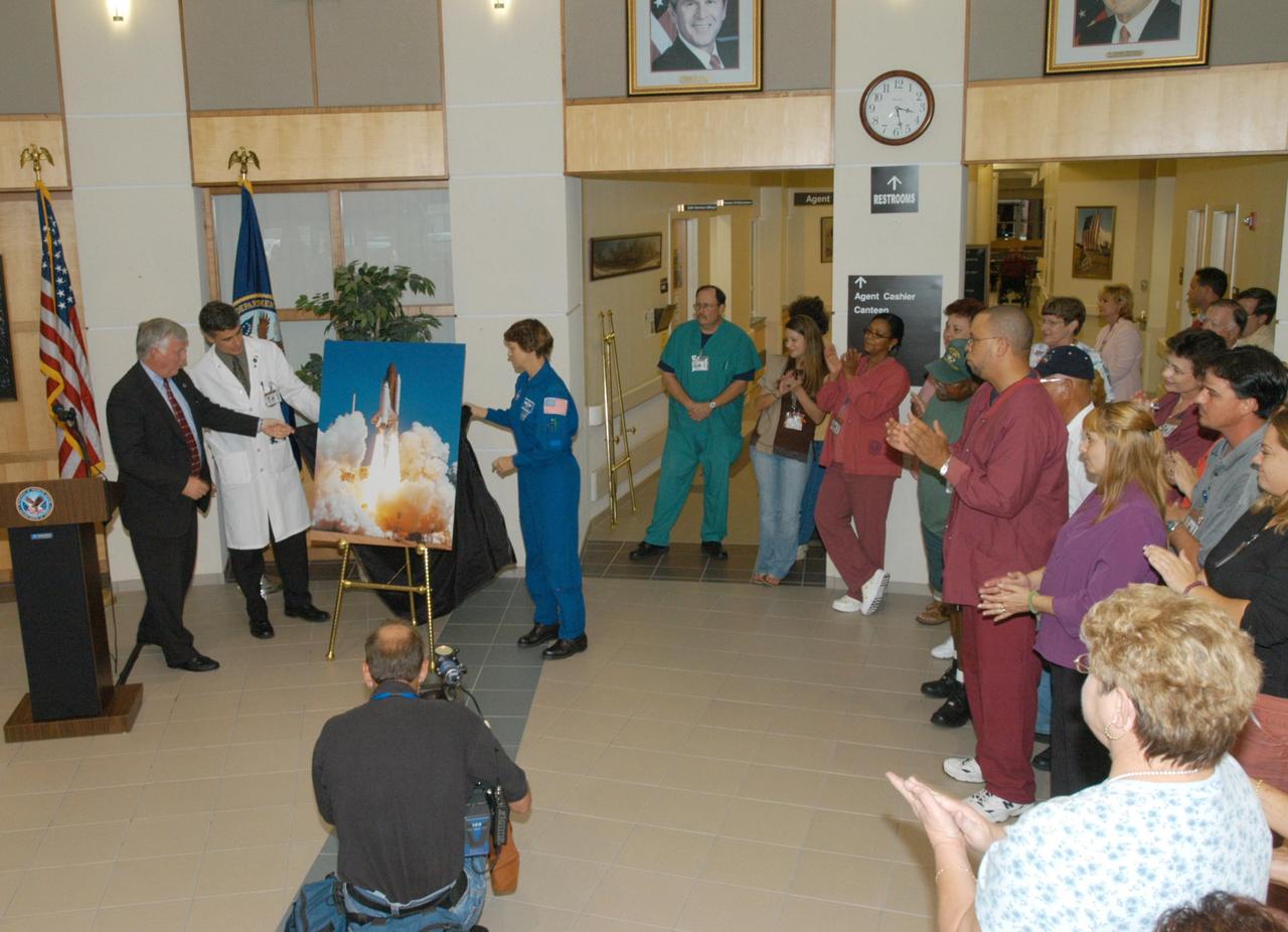 KENNEDY SPACE CENTER, FLA. -   Center Director Jim Kennedy (far left) and STS-114 Mission Commander Eileen Collins (center) present a photo of the launch of Discovery to Dr. Thomas Howard, chief medical officer of the V.A. Outpatient Clinic in Viera, Fla.  The presentation is part of the dedication of a hospital wing in honor of space shuttle Discovery, to be known as the Discovery wing. Collins and her crew have returned to Florida especially for a celebration in the KSC Visitor Complex of the successful return to flight mission that launched July 26 of this year.