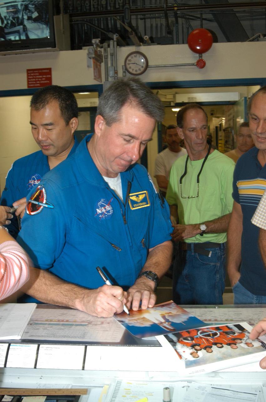 KENNEDY SPACE CENTER, FLA. - In Kennedy Space Center’s Orbiter Processing Facility Bay 3, STS-114 Mission Specialist Stephen Robinson autographs photos for employees. Behind him, at left, is Mission Specialist Soichi Noguchi. They and other crew members are visiting several sites during their return to KSC. They have returned to Florida especially for a celebration in the KSC Visitor Complex of the successful return to flight mission that launched July 26 of this year.