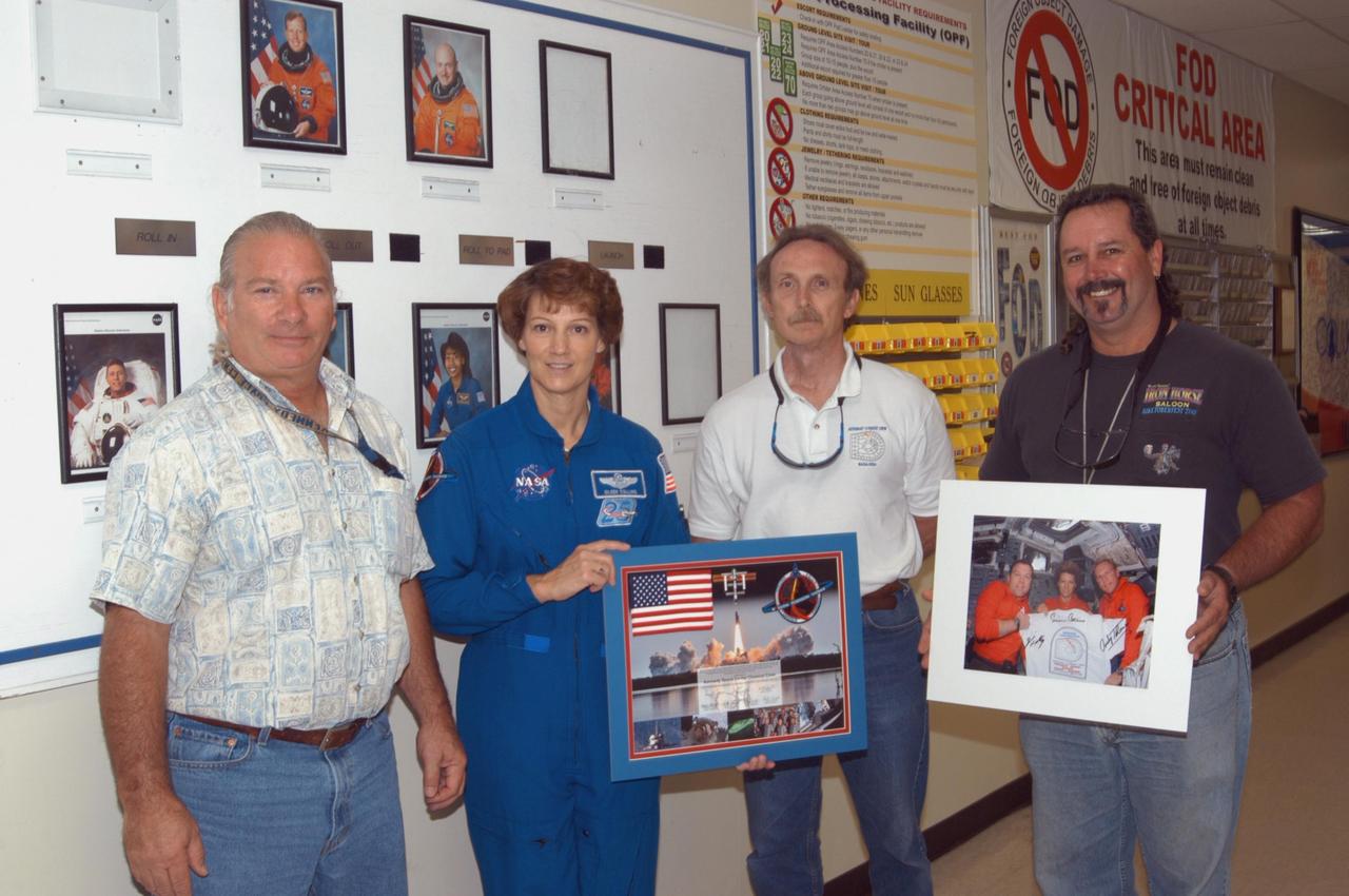 KENNEDY SPACE CENTER, FLA. -  In Kennedy Space Center’s Orbiter Processing Facility Bay 3, STS-114 Mission Commander Eileen Collins poses with closeout crew members Paul Arnold, Al Schmidt and Tim Seymour after presented them the photos they are holding.  Collins and other crew members are visiting several sites during their return to KSC. They have returned to Florida especially for a celebration in the KSC Visitor Complex of the successful return to flight mission that launched July 26 of this year.