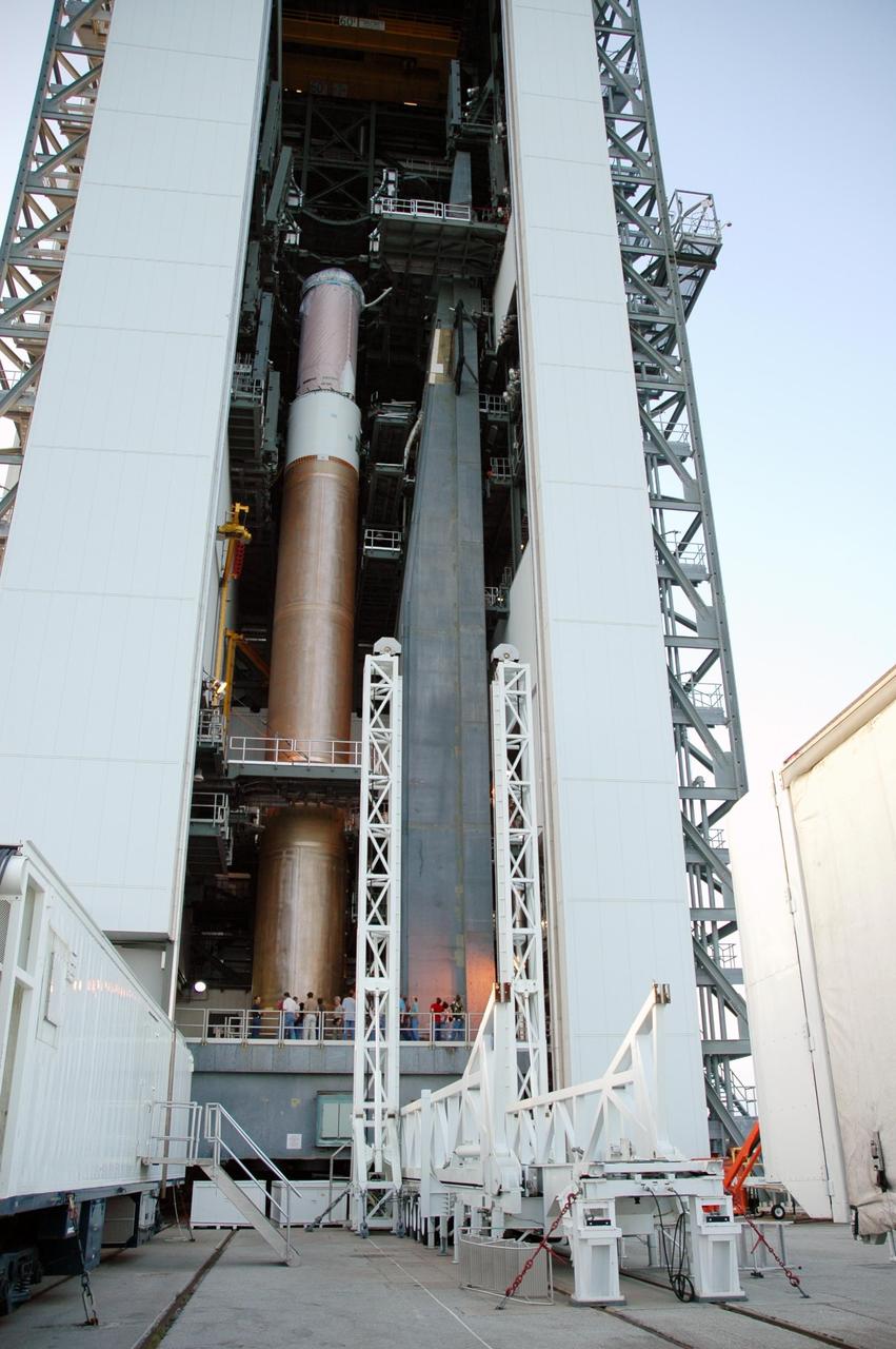 KENNEDY SPACE CENTER, FLA. - On Launch Complex 41 at Cape Canaveral Air Force Station, workers prepare the Lockheed Martin Atlas V rocket for mating of the solid rocket boosters. In the foreground is the trailer used to transport the boosters to the pad. The Atlas V is the launch vehicle for the Pluto-bound New Horizons spacecraft that will make the first reconnaissance of Pluto and its moon, Charon - a "double planet" and the last planet in our solar system to be visited by spacecraft. As it approaches Pluto, the spacecraft will look for ultraviolet emission from Pluto's atmosphere and make the best global maps of Pluto and Charon in green, blue, red and a special wavelength that is sensitive to methane frost on the surface. It will also take spectral maps in the near infrared, telling the science team about Pluto's and Charon’s surface compositions and locations and temperatures of these materials. When the spacecraft is closest to Pluto or its moon, it will take close-up pictures in both visible and near-infrared wavelengths. The mission will then visit one or more objects in the Kuiper Belt region beyond Neptune. New Horizons is scheduled to launch in January 2006, swing past Jupiter for a gravity boost and scientific studies in February or March 2007, and reach Pluto and Charon in July 2015.