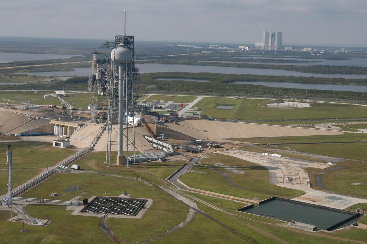 KENNEDY SPACE CENTER, FLA. - Another aerial view of Launch Pad 39A at NASA Kennedy Space Center in Florida. In the background at right is the Vehicle Assembly Building. Atop the fixed service structure is the 80-foot-tall lightning mast. In front is the 290-foot-tall water tower that holds 300,000 gallons of water used at launch for sound suppression to protect the orbiter and its payloads from damage by acoustical energy and rocket exhaust reflected from the flame trench and Mobile Launcher Platform during launch.