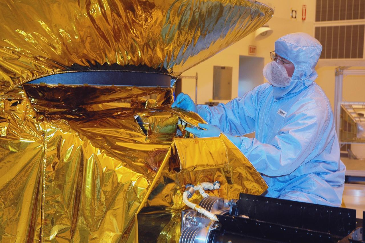 KENNEDY SPACE CENTER, FLA. - At NASA Kennedy Space Center’s Payload Hazardous Servicing Facility, a technician from the Applied Physics Laboratory adjusts part of the blanket that is being installed as a heat shield around the New Horizons spacecraft. Carrying seven scientific instruments, the compact 1,060-pound New Horizons probe will characterize the global geology and geomorphology of Pluto and its moon Charon, map their surface compositions and temperatures, and examine Pluto's complex atmosphere. After that, flybys of Kuiper Belt objects from even farther in the solar system may be undertaken in an extended mission. New Horizons is the first mission in NASA's New Frontiers program of medium-class planetary missions. The spacecraft, designed for NASA by the Johns Hopkins University Applied Physics Laboratory in Laurel, Md., will fly by Pluto and Charon as early as summer 2015.