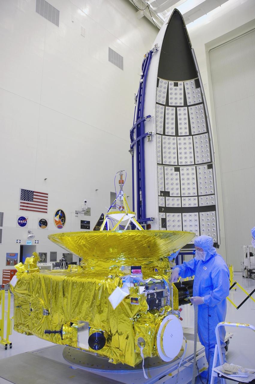 KENNEDY SPACE CENTER, FLA. - In the clean room at KSC’s Payload Hazardous Servicing Facility, the New Horizons spacecraft is prepared for a media event. Photographers and reporters will be able to photograph the New Horizons spacecraft and talk with project management and test team members from NASA and the Johns Hopkins University Applied Physics Laboratory. Seen behind the spacecraft is one half of the fairing that will enclose it for launch, scheduled for January 2006. Carrying seven scientific instruments, the compact 1,060-pound New Horizons probe will characterize the global geology and geomorphology of Pluto and its moon Charon, map their surface compositions and temperatures, and examine Pluto's complex atmosphere. After that, flybys of Kuiper Belt objects from even farther in the solar system may be undertaken in an extended mission. New Horizons is the first mission in NASA's New Frontiers program of medium-class planetary missions. The spacecraft, designed for NASA by the Johns Hopkins University Applied Physics Laboratory in Laurel, Md., will fly by Pluto and Charon as early as summer 2015.