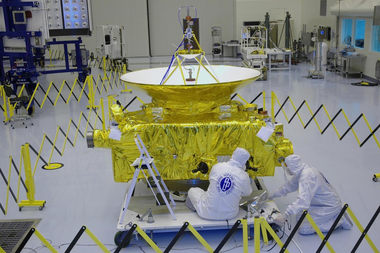 KENNEDY SPACE CENTER, FLA. - In the clean room at KSC’s Payload Hazardous Servicing Facility, the New Horizons spacecraft is being prepared for a media event. Photographers and reporters will be able to photograph the New Horizons spacecraft and talk with project management and test team members from NASA and the Johns Hopkins University Applied Physics Laboratory. Seen behind the spacecraft is one half of the fairing that will enclose it for launch, scheduled for January 2006. Carrying seven scientific instruments, the compact 1,060-pound New Horizons probe will characterize the global geology and geomorphology of Pluto and its moon Charon, map their surface compositions and temperatures, and examine Pluto's complex atmosphere. After that, flybys of Kuiper Belt objects from even farther in the solar system may be undertaken in an extended mission. New Horizons is the first mission in NASA's New Frontiers program of medium-class planetary missions. The spacecraft, designed for NASA by the Johns Hopkins University Applied Physics Laboratory in Laurel, Md., will fly by Pluto and Charon as early as summer 2015.