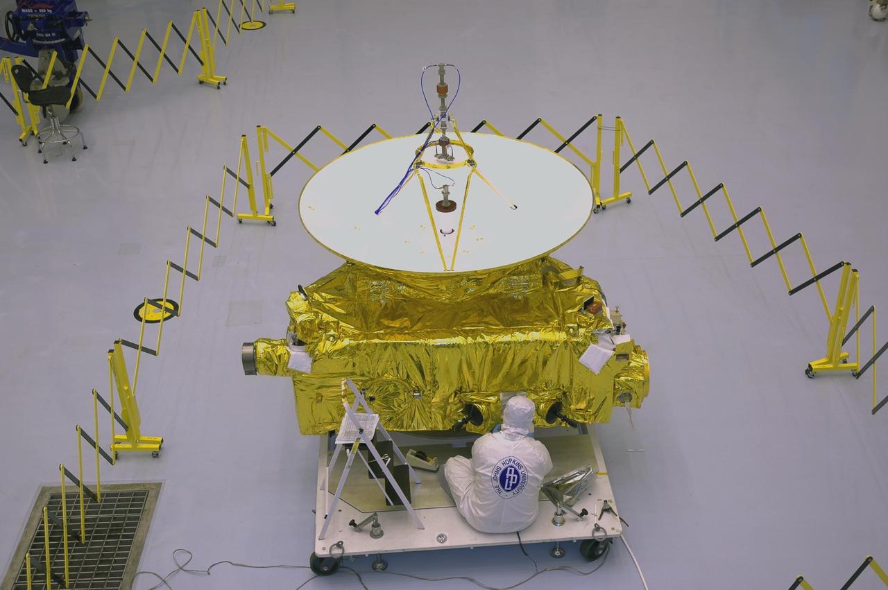 KENNEDY SPACE CENTER, FLA. - In the clean room at KSC’s Payload Hazardous Servicing Facility, the New Horizons spacecraft is ready for a media event. Photographers and reporters will be able to photograph the New Horizons spacecraft and talk with project management and test team members from NASA and the Johns Hopkins University Applied Physics Laboratory. Seen behind the spacecraft is one half of the fairing that will enclose it for launch, scheduled for January 2006. Carrying seven scientific instruments, the compact 1,060-pound New Horizons probe will characterize the global geology and geomorphology of Pluto and its moon Charon, map their surface compositions and temperatures, and examine Pluto's complex atmosphere. After that, flybys of Kuiper Belt objects from even farther in the solar system may be undertaken in an extended mission. New Horizons is the first mission in NASA's New Frontiers program of medium-class planetary missions. The spacecraft, designed for NASA by the Johns Hopkins University Applied Physics Laboratory in Laurel, Md., will fly by Pluto and Charon as early as summer 2015.
