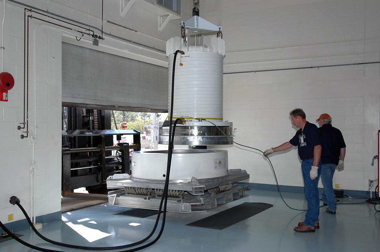 KENNEDY SPACE CENTER, FLA. - Bob Tessmer and Dave Nobles lift the radioisotope thermoelectric generator (RTG) container after its move inside the RTG facility at Kennedy Space Center. The RTG is the baseline power supply for the NASA’s New Horizons spacecraft, scheduled to launch in January 2006 on a journey to Pluto and its moon, Charon. As it approaches Pluto, the spacecraft will look for ultraviolet emission from Pluto's atmosphere and make the best global maps of Pluto and Charon in green, blue, red and a special wavelength that is sensitive to methane frost on the surface. It will also take spectral maps in the near infrared, telling the science team about Pluto's and Charon's surface compositions and locations and temperatures of these materials. When the spacecraft is closest to Pluto or its moon, it will take close-up pictures in both visible and near-infrared wavelengths. It is expected to reach Pluto in July 2015.