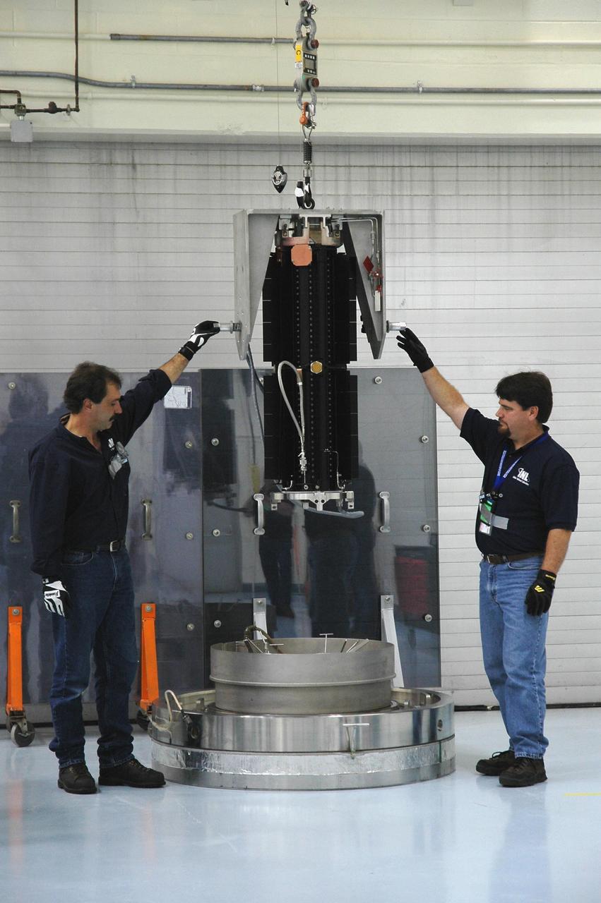 KENNEDY SPACE CENTER, FLA. - In the RTG Facility at Kennedy Space Center, Jim Wojciechowski (left) and Rhett Rovig lift the radioisotope thermoelectric generator (RTG) from its stand to place it on a cart. It will then be maneuvered to a horizontal position. The RTG is the baseline power supply for the NASA’s New Horizons spacecraft, scheduled to launch in January 2006 on a journey to Pluto and its moon, Charon. As it approaches Pluto, the spacecraft will look for ultraviolet emission from Pluto's atmosphere and make the best global maps of Pluto and Charon in green, blue, red and a special wavelength that is sensitive to methane frost on the surface. It will also take spectral maps in the near infrared, telling the science team about Pluto's and Charon's surface compositions and locations and temperatures of these materials. When the spacecraft is closest to Pluto or its moon, it will take close-up pictures in both visible and near-infrared wavelengths. It is expected to reach Pluto in July 2015.