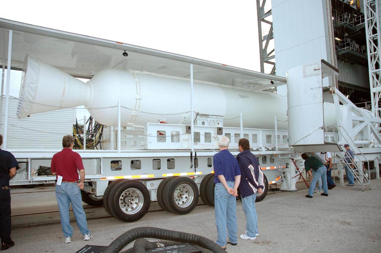 KENNEDY SPACE CENTER, FLA. - Workers on Launch Complex 41 at Cape Canaveral Air Force Station in Florida stand by as the solid rocket booster in front of them is prepared to be raised to vertical. The booster rocket will be mated, along with others, to the Atlas V already in the Vertical Integration Facility, at right. The Atlas V is the launch vehicle for NASA’s New Horizons spacecraft, scheduled to launch in January 2006 on a journey to Pluto and its moon, Charon.