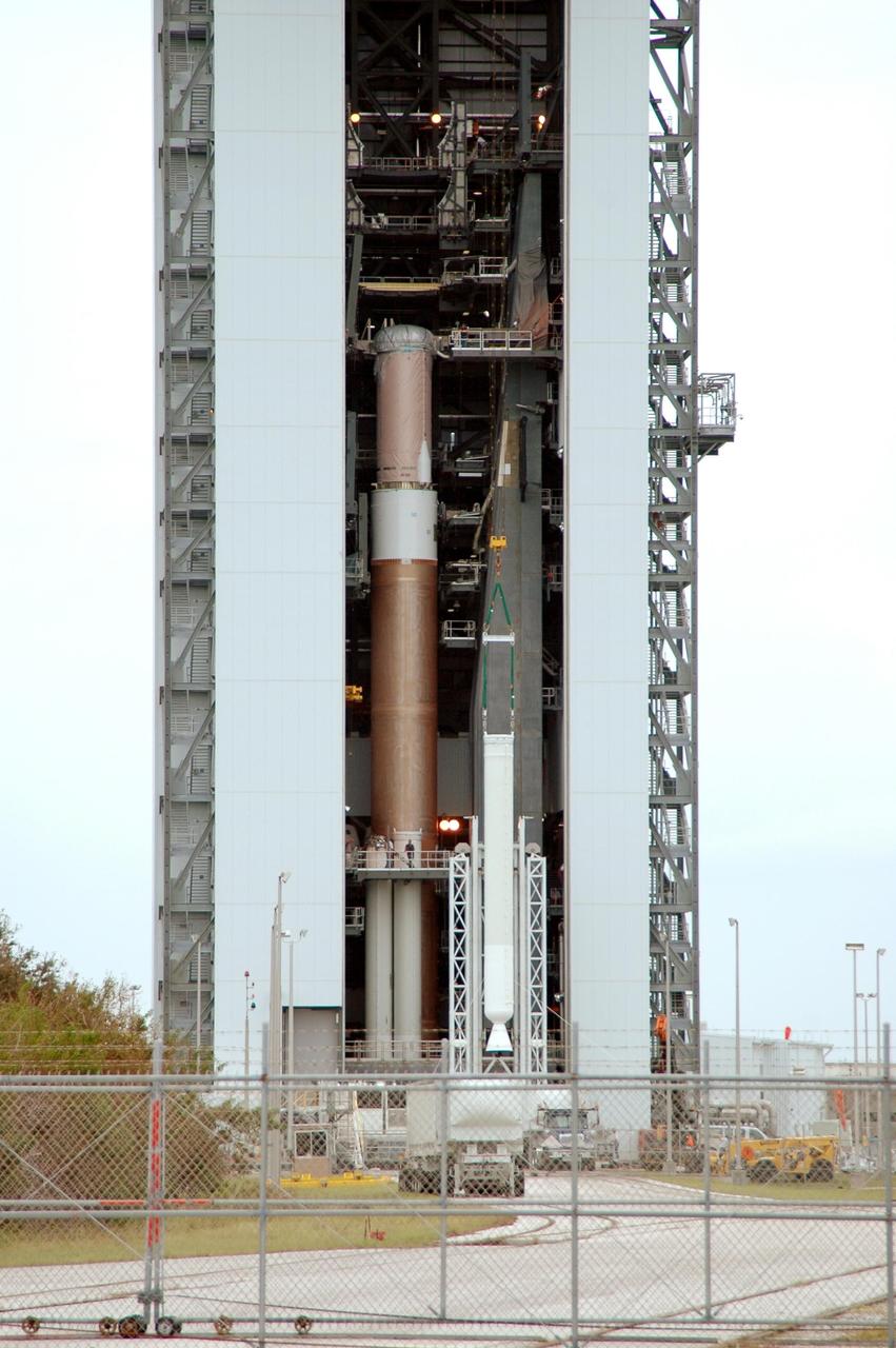 KENNEDY SPACE CENTER, FLA. - A solid rocket booster, on the right, is lifted up into the Vertical Integration Facility on Launch Complex 41 at Cape Canaveral Air Force Station in Florida. The booster rocket will be mated, along with others, to the Atlas V, at left. The Atlas V is the launch vehicle for NASA’s New Horizons spacecraft, scheduled to launch in January 2006 on a journey to Pluto and its moon, Charon.