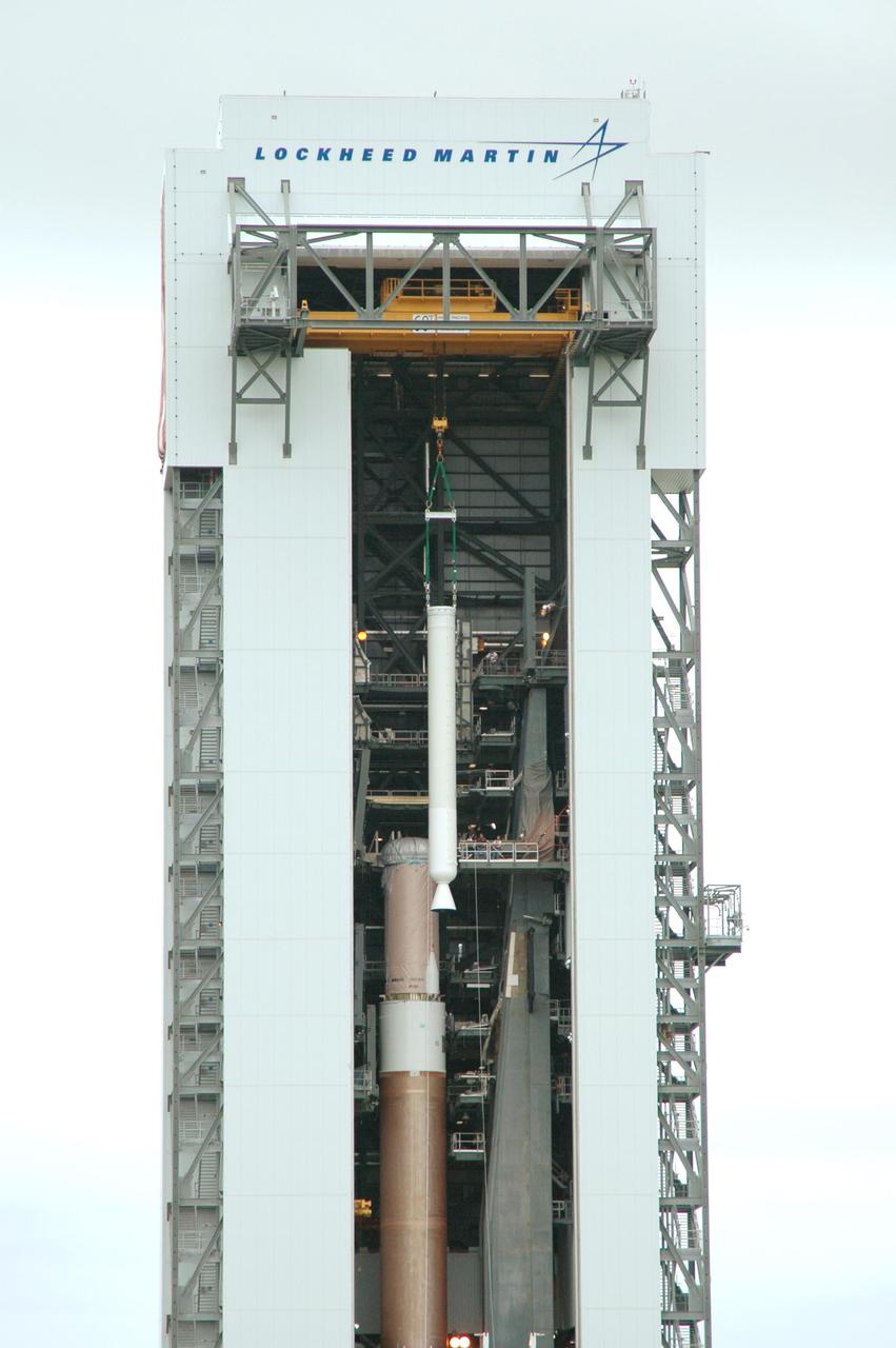 KENNEDY SPACE CENTER, FLA. - In the Vertical Integration Facility on Launch Complex 41 at Cape Canaveral Air Force Station in Florida, a solid rocket booster is being lowered into position on the Atlas V rocket at left. The Atlas V is the launch vehicle for NASA’s New Horizons spacecraft, scheduled to launch in January 2006 on a journey to Pluto and its moon, Charon.