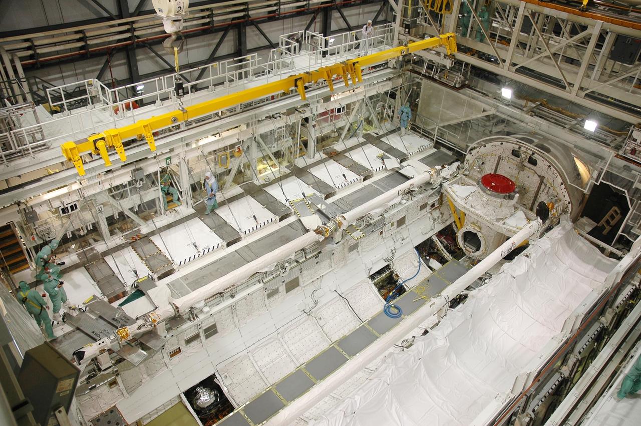 KENNEDY SPACE CENTER, FLA. - In the Orbiter Processing Facility Bay 1 at NASA Kennedy Space Center, a crane is lowered toward the remote manipulator system boom in Atlantis’ payload bay.  The boom is being removed from Atlantis and will be temporarily stored.  The RMS includes the electromechanical arm that maneuvers a payload from the payload bay of the orbiter to its deployment position and then releases it. It can also grapple a free-flying payload, maneuver it to the payload bay of the orbiter and berth it in the orbiter. The RMS arm is 50 feet 3 inches long and 15 inches in diameter. It weighs 905 pounds, and the total system weighs 994 pounds. The RMS has six joints that correspond roughly to the joints of the human arm, with shoulder yaw and pitch joints; an elbow pitch joint; and wrist pitch, yaw and roll joints. The end effector is the unit at the end of the wrist that actually grabs, or grapples, the payload.