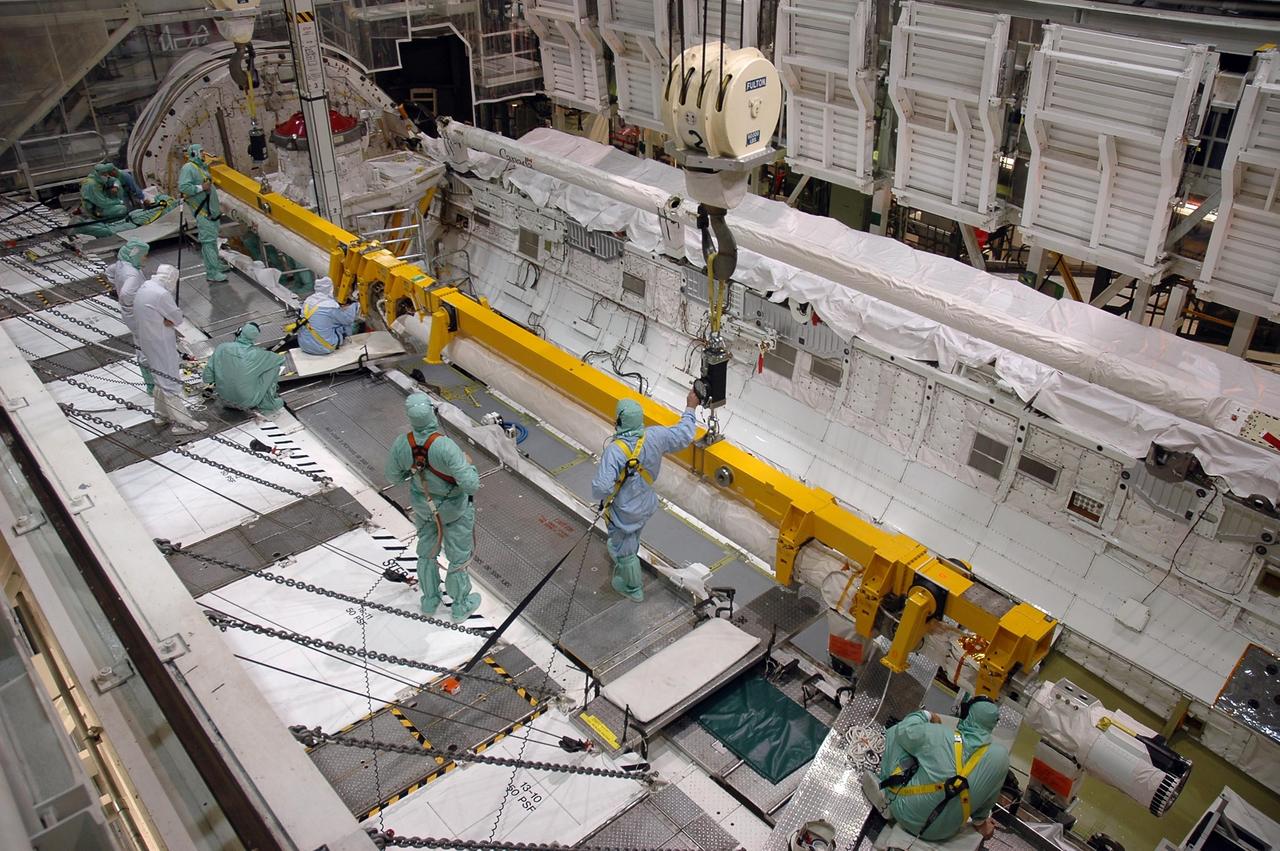 KENNEDY SPACE CENTER, FLA. - In the Orbiter Processing Facility Bay 1 at NASA Kennedy Space Center, workers secure a crane to the remote manipulator system boom in Atlantis’ payload bay. The boom is being removed from Atlantis and will be temporarily stored.. The RMS includes the electromechanical arm that maneuvers a payload from the payload bay of the orbiter to its deployment position and then releases it. It can also grapple a free-flying payload, maneuver it to the payload bay of the orbiter and berth it in the orbiter. The RMS arm is 50 feet 3 inches long and 15 inches in diameter. It weighs 905 pounds, and the total system weighs 994 pounds. The RMS has six joints that correspond roughly to the joints of the human arm, with shoulder yaw and pitch joints; an elbow pitch joint; and wrist pitch, yaw and roll joints. The end effector is the unit at the end of the wrist that actually grabs, or grapples, the payload.