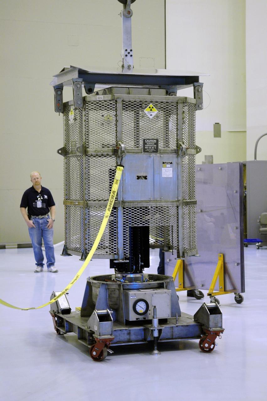 KENNEDY SPACE CENTER, FLA. - In the Payload Hazardous Servicing Facility, a metal canister is lowered over the radioisotope thermoelectric generator (RTG). The canister will protect the RTG while it is being moved to the RTG facility. The RTG underwent a fit check with the spacecraft. The RTG is the baseline power supply for the New Horizons, scheduled to launch in January 2006 on a journey to Pluto and its moon, Charon. As it approaches Pluto, the spacecraft will look for ultraviolet emission from Pluto's atmosphere and make the best global maps of Pluto and Charon in green, blue, red and a special wavelength that is sensitive to methane frost on the surface. It will also take spectral maps in the near infrared, telling the science team about Pluto's and Charon's surface compositions and locations and temperatures of these materials. When the spacecraft is closest to Pluto or its moon, it will take close-up pictures in both visible and near-infrared wavelengths. It is expected to reach Pluto in July 2015.