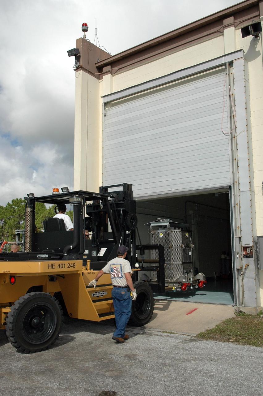 KENNEDY SPACE CENTER, FLA. - The radioisotope thermoelectric generator (RTG), enclosed in a metal canister, is moved into the RTG Facility. The RTG is being returned from the Payload Hazardous Servicing Facility where it underwent a fit check with the spacecraft. The RTG is the baseline power supply for the New Horizons, scheduled to launch in January 2006 on a journey to Pluto and its moon, Charon. As it approaches Pluto, the spacecraft will look for ultraviolet emission from Pluto's atmosphere and make the best global maps of Pluto and Charon in green, blue, red and a special wavelength that is sensitive to methane frost on the surface. It will also take spectral maps in the near infrared, telling the science team about Pluto's and Charon's surface compositions and locations and temperatures of these materials. When the spacecraft is closest to Pluto or its moon, it will take close-up pictures in both visible and near-infrared wavelengths. It is expected to reach Pluto in July 2015.