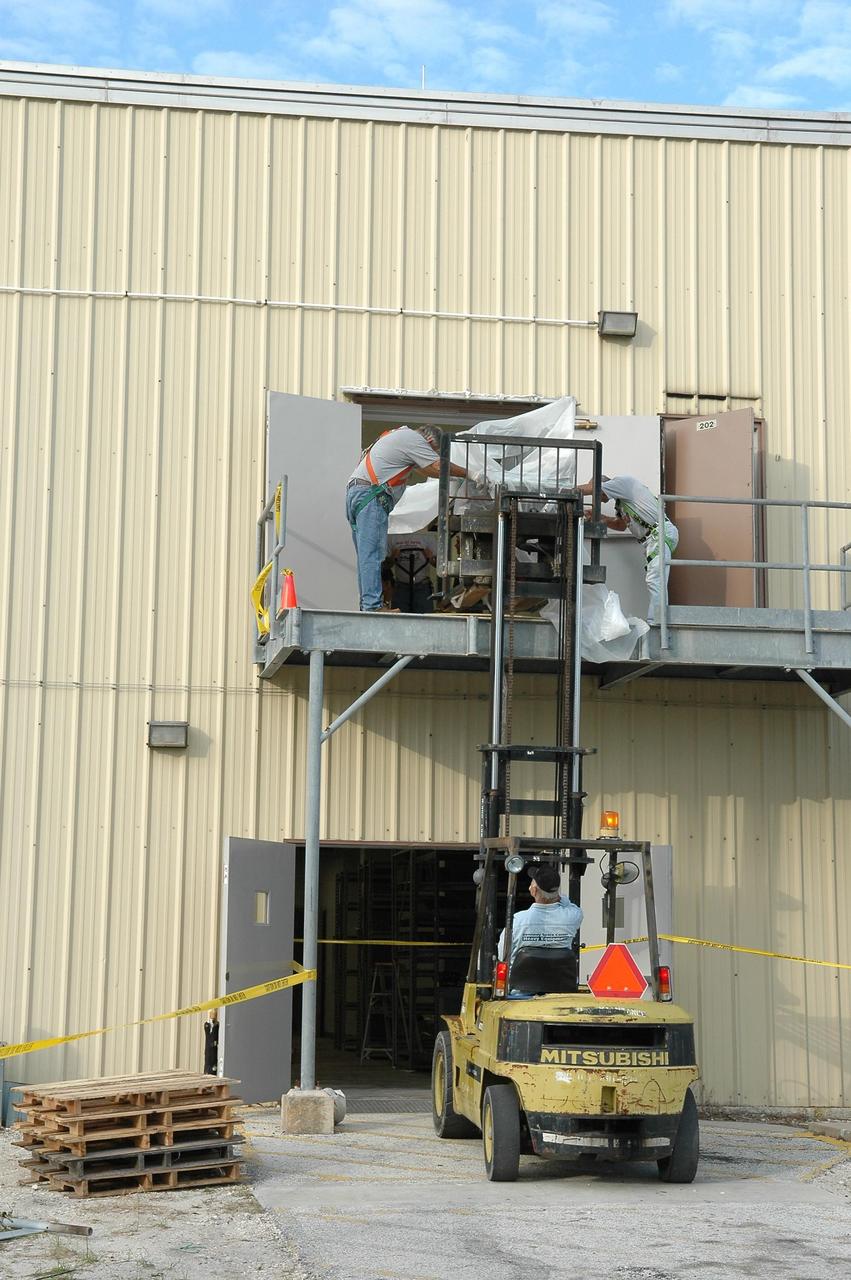 KENNEDY SPACE CENTER, FLA. - Employees at NASA Kennedy Space Center are moving equipment out of the RLV Hangar, where it was stored, and returning it to the Thermal Protection System (TPS) facility.  The upper floor of the facility, where soft material was processed,  was damaged during the 2004 hurricanes.  While the TPS facility was being repaired, normal work activity was done in the hangar.