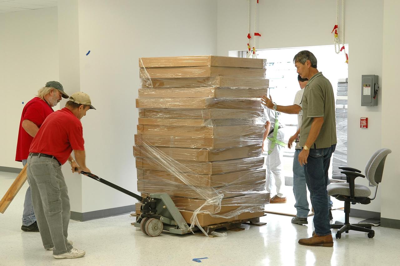 KENNEDY SPACE CENTER, FLA. - Inside the RLV Hangar at NASA Kennedy Space Center, employees move equipment being returned to the Thermal Protection System (TPS) facility. The upper floor, where soft material was processed,  was damaged during the 2004 hurricanes.  While the TPS facility was being repaired, normal work activity was done in the hangar.